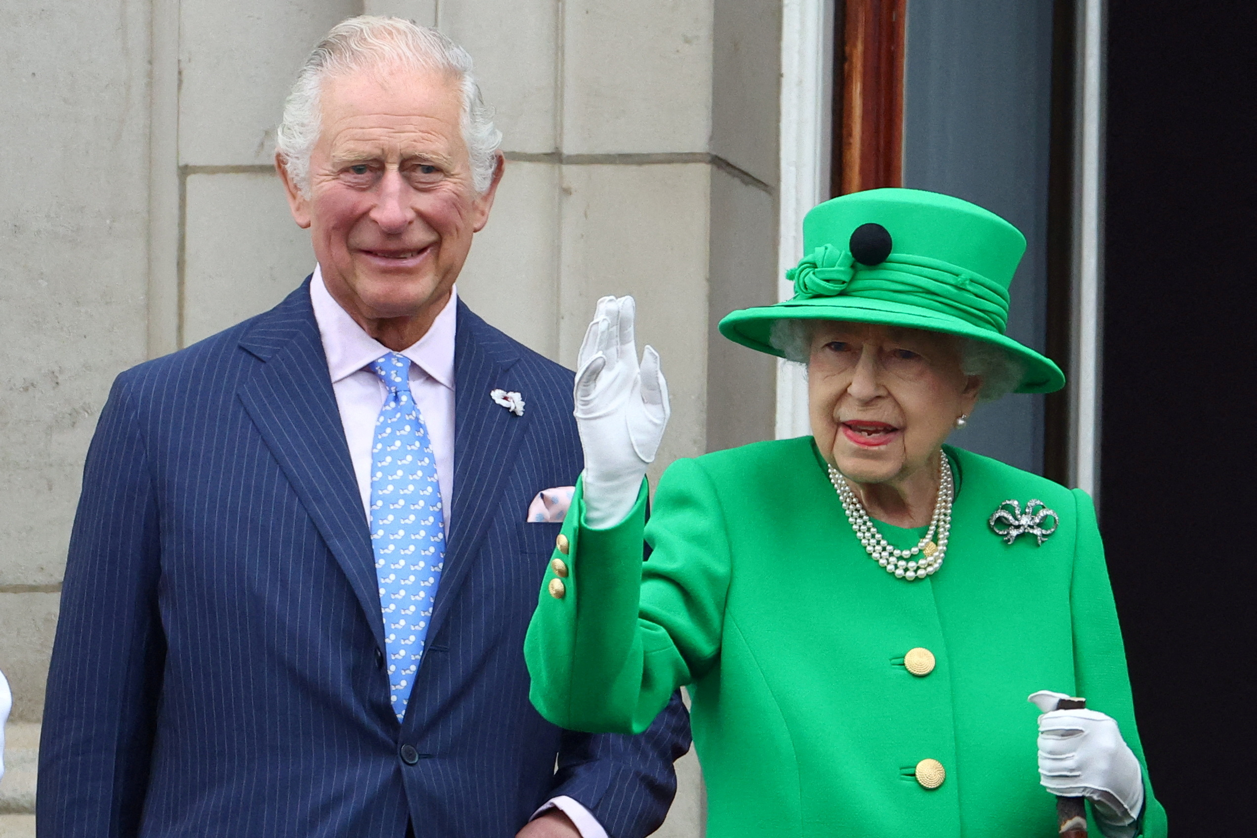 Queen Elizabeth II waving with her son Charles in tow.