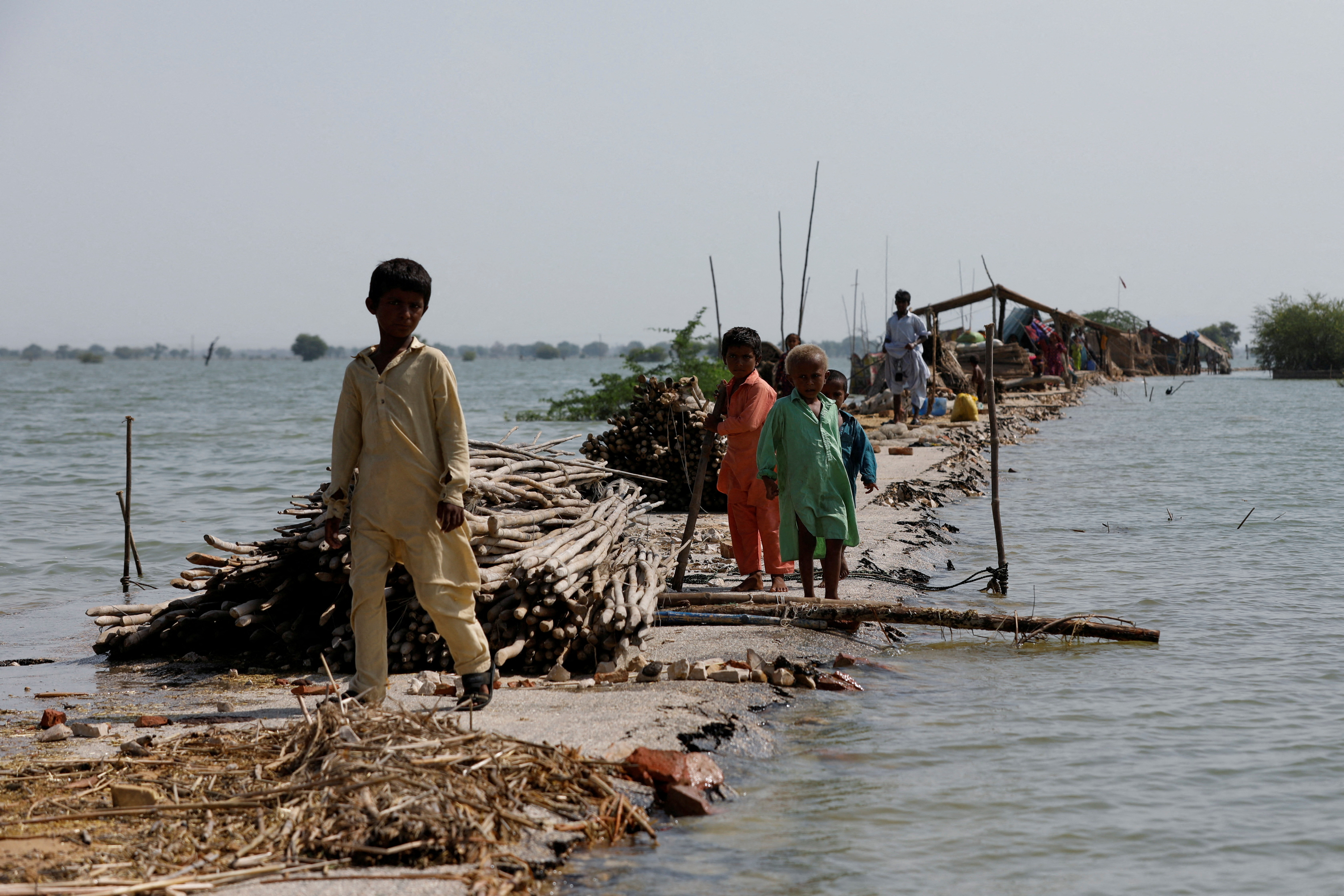 Children stand as their family takes refuge along a damaged road amid flood, following rains and floods during the monsoon season in Bajara village, at the banks of Manchar lake, in Sehwan, Pakistan September 6, 2022.