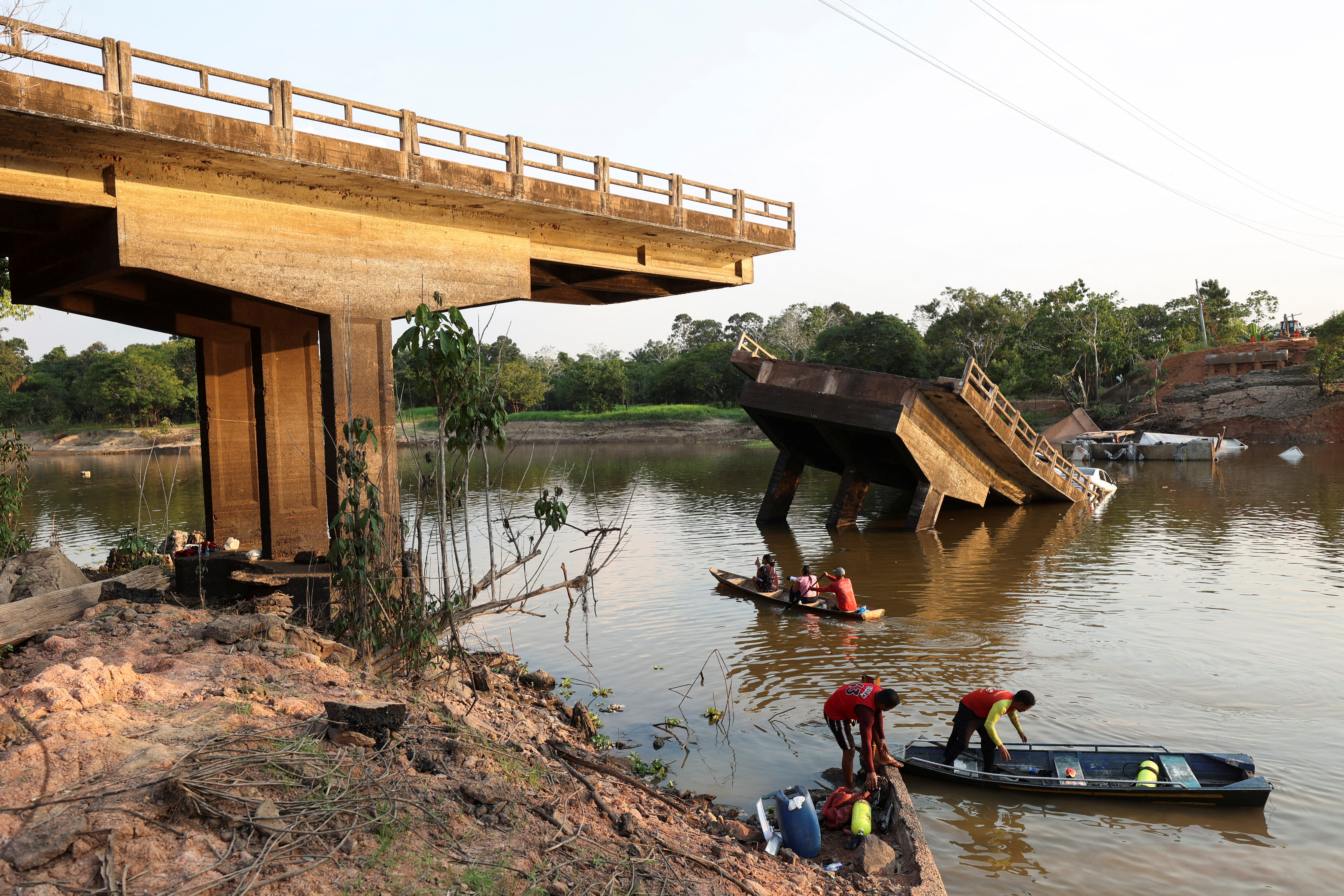 The collapsed bridge with part of it in the river and rescuers in boats looking for survivors.