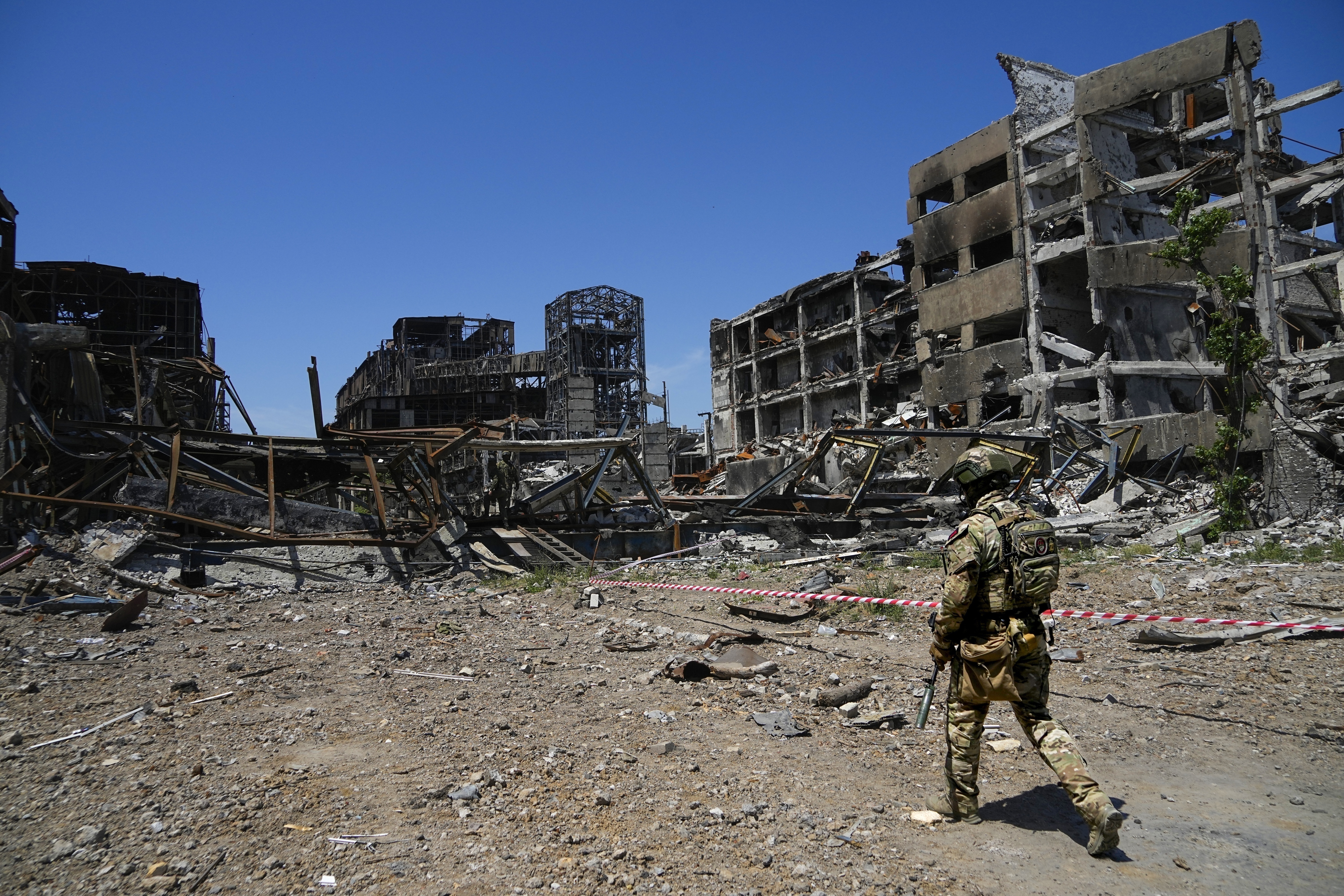Russian soldier walks in front of the damaged Metallurgical Combine Azovstal plant