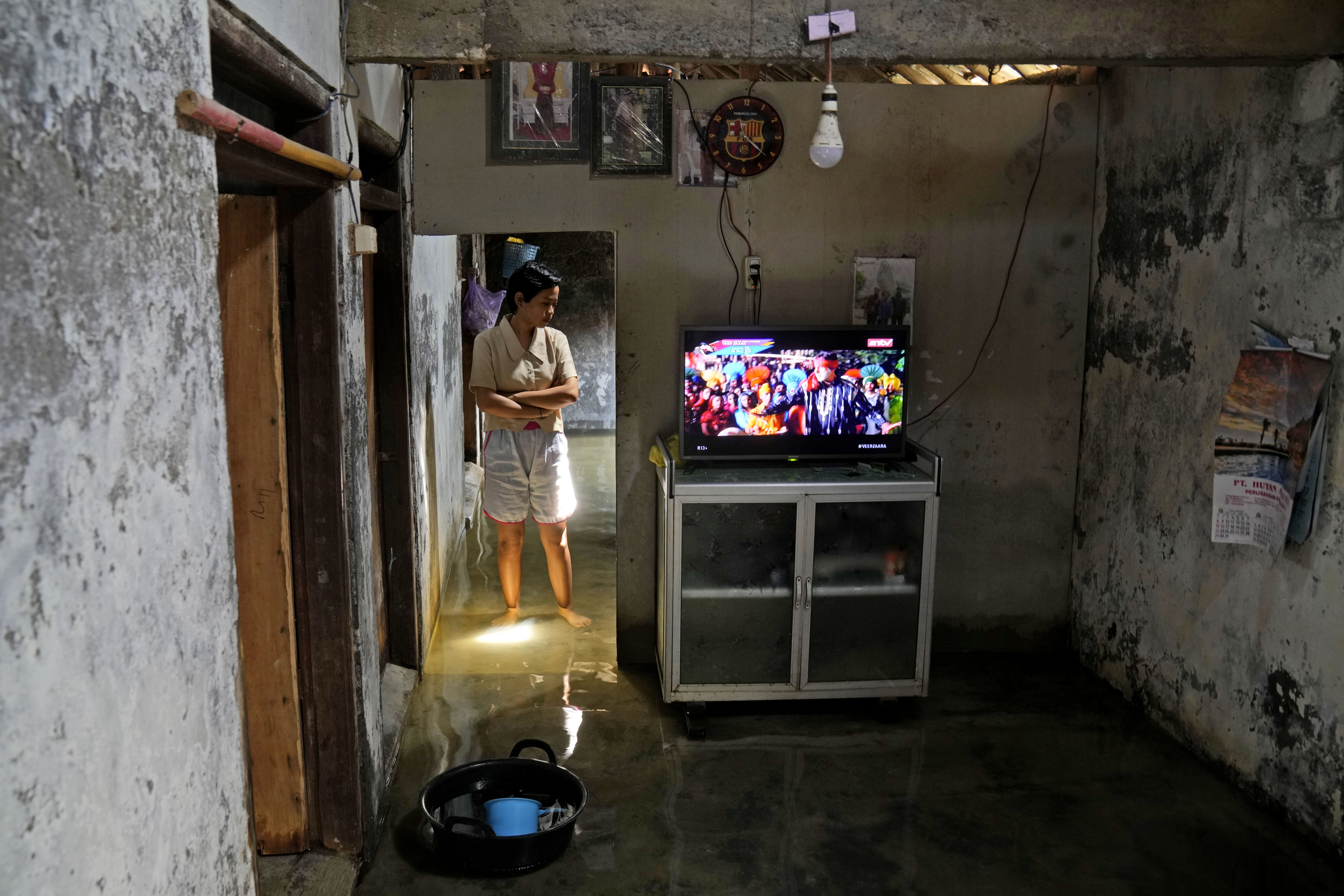 Dwi Ulfani stands inside her flooded home