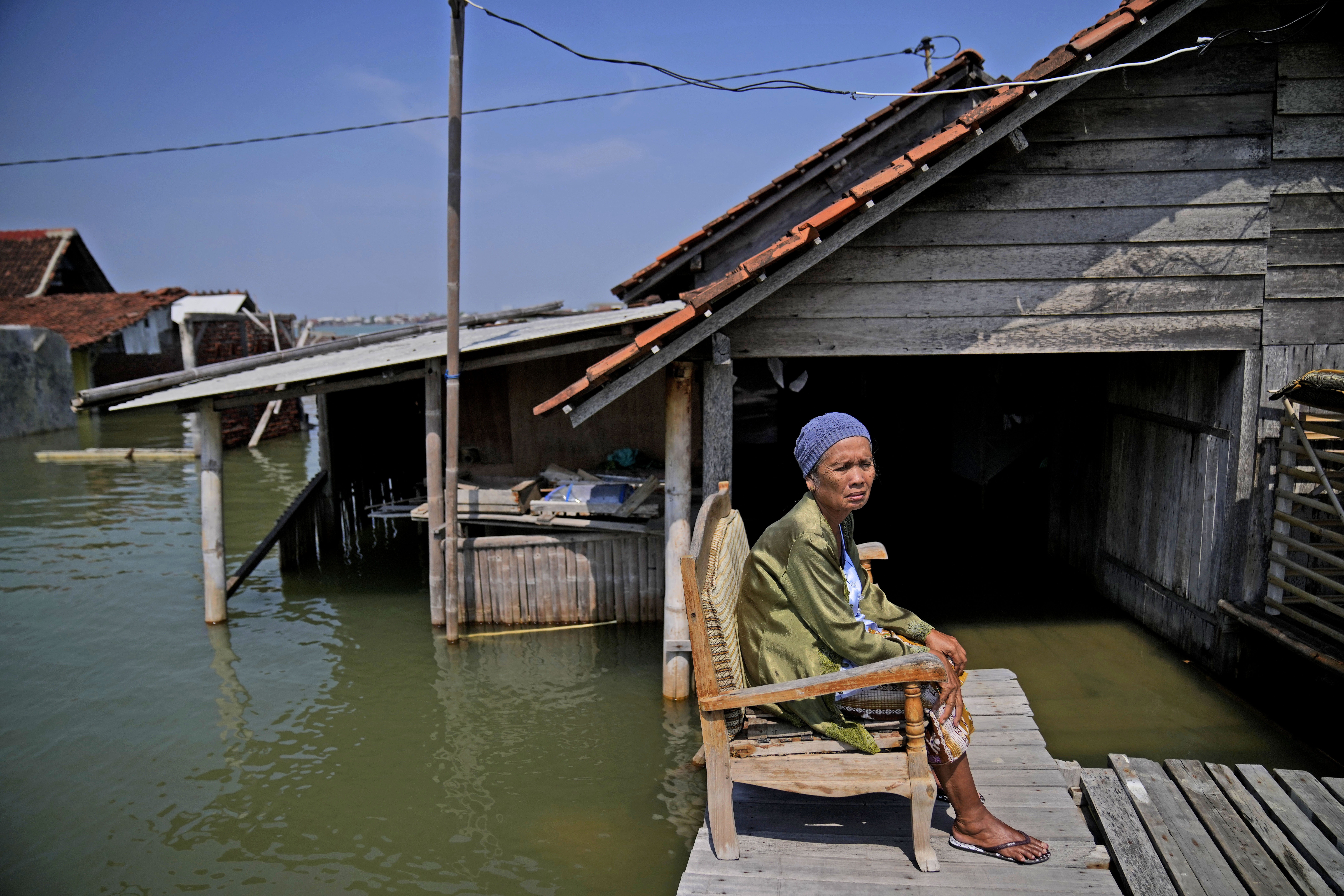 Mar'iah sits outside her house while waiting for the flood water to subside