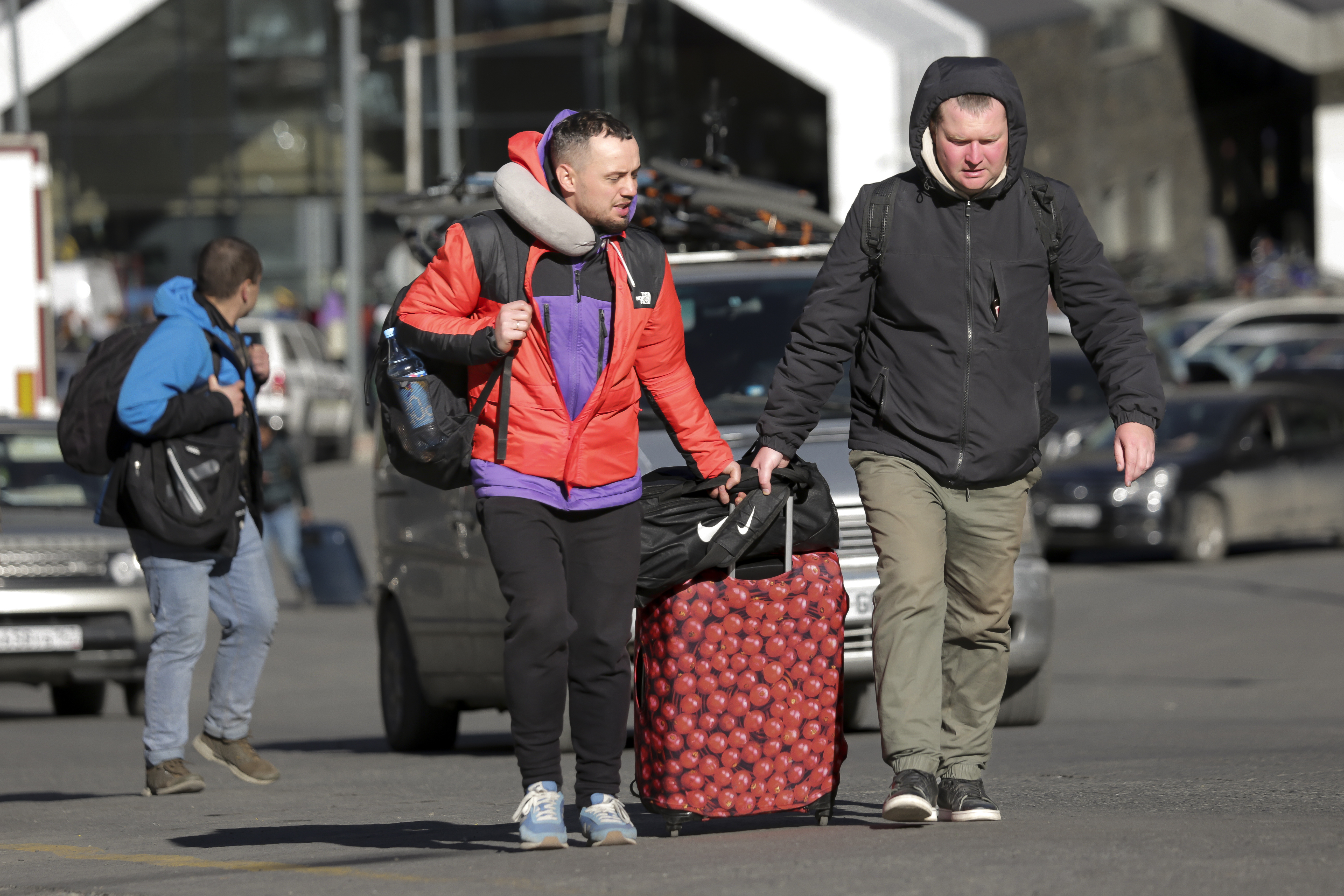 Russian men walk after crossing the border at Verkhny Lars between Georgia and Russia in Georgia, Tuesday, Sept. 27, 2022. Long lines of vehicles have formed at a border crossing between Russia's North Ossetia region and Georgia after Moscow announced a partial military mobilization. A day after President Vladimir Putin ordered a partial mobilization to bolster his troops in Ukraine, many Russians are leaving their homes. (AP Photo/Zurab Tsertsvadze)