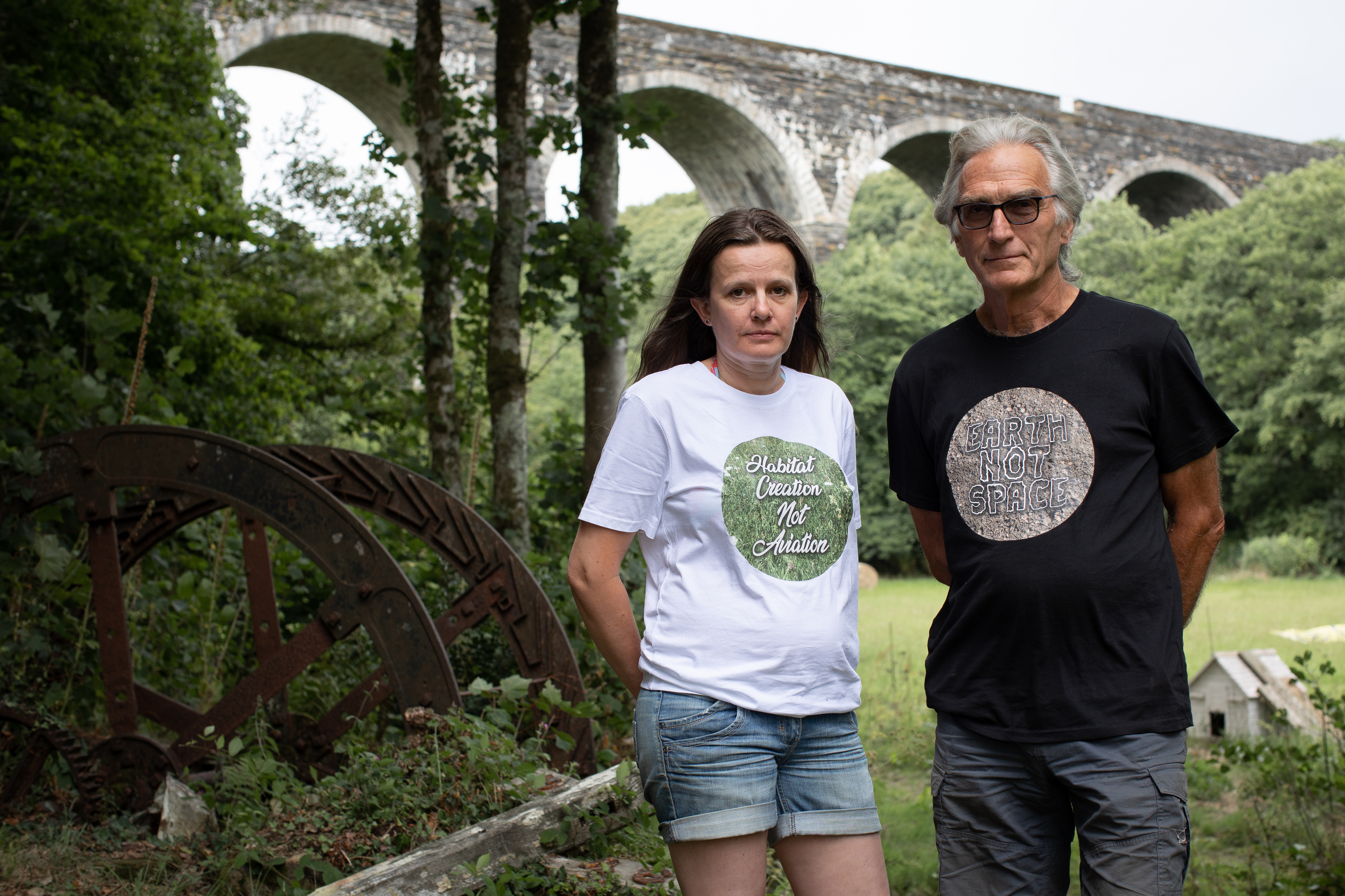 A photo of two people standing next to each other outside surrounded by greenery.