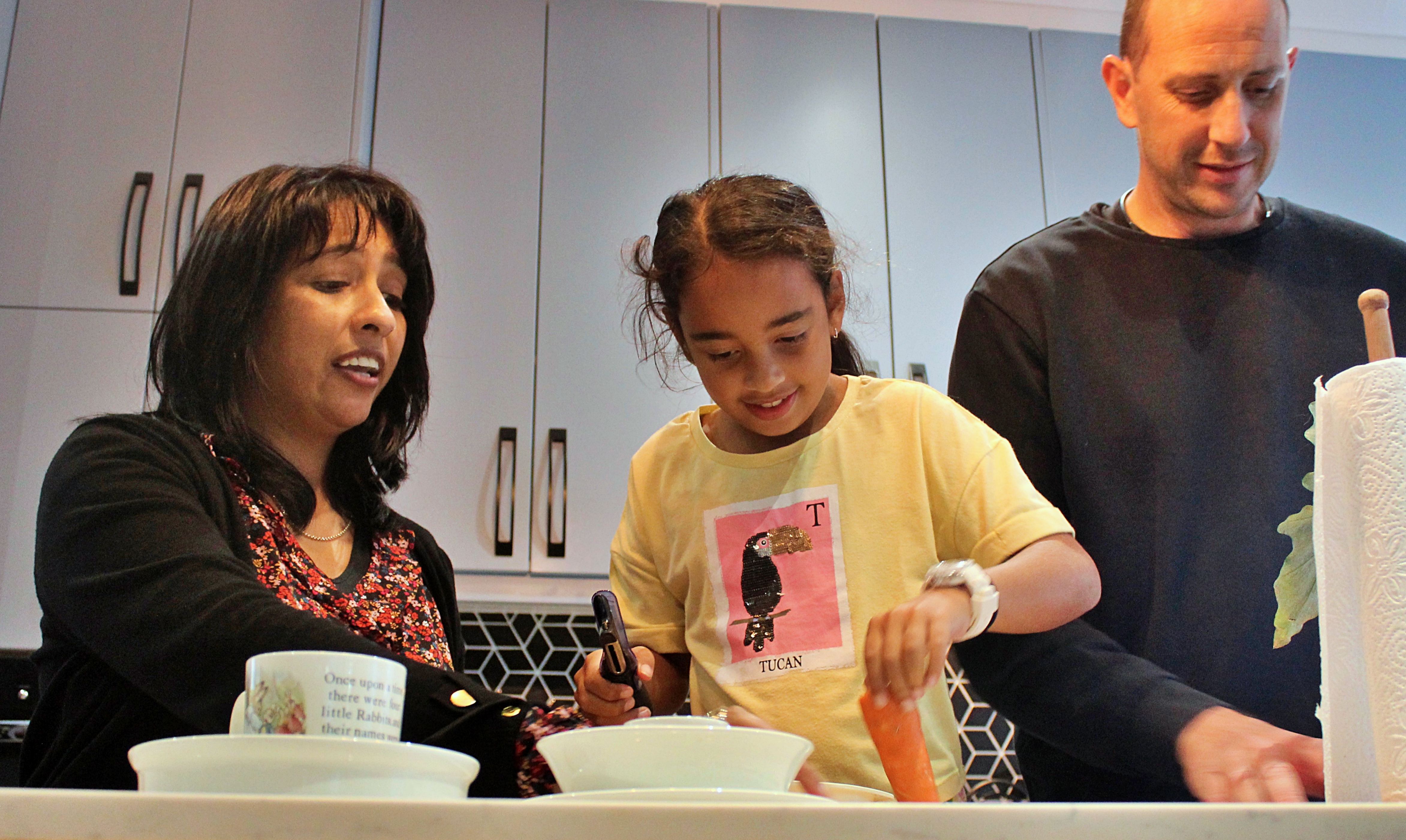 A man, woman and a child prepare food in a kitchen