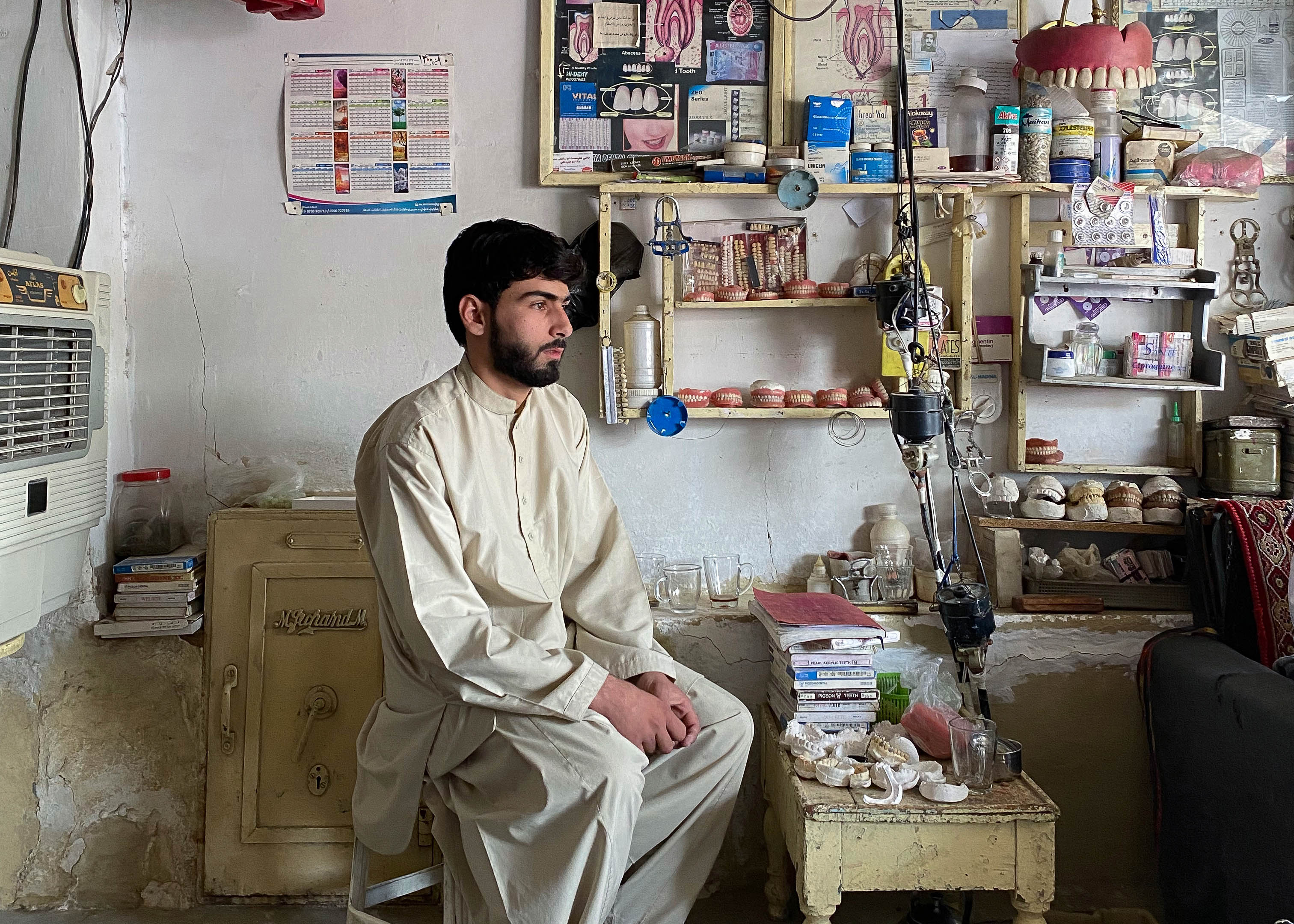 A photo of 16-year-old Ahmed Waris sitting in front of a table with denture samples.
