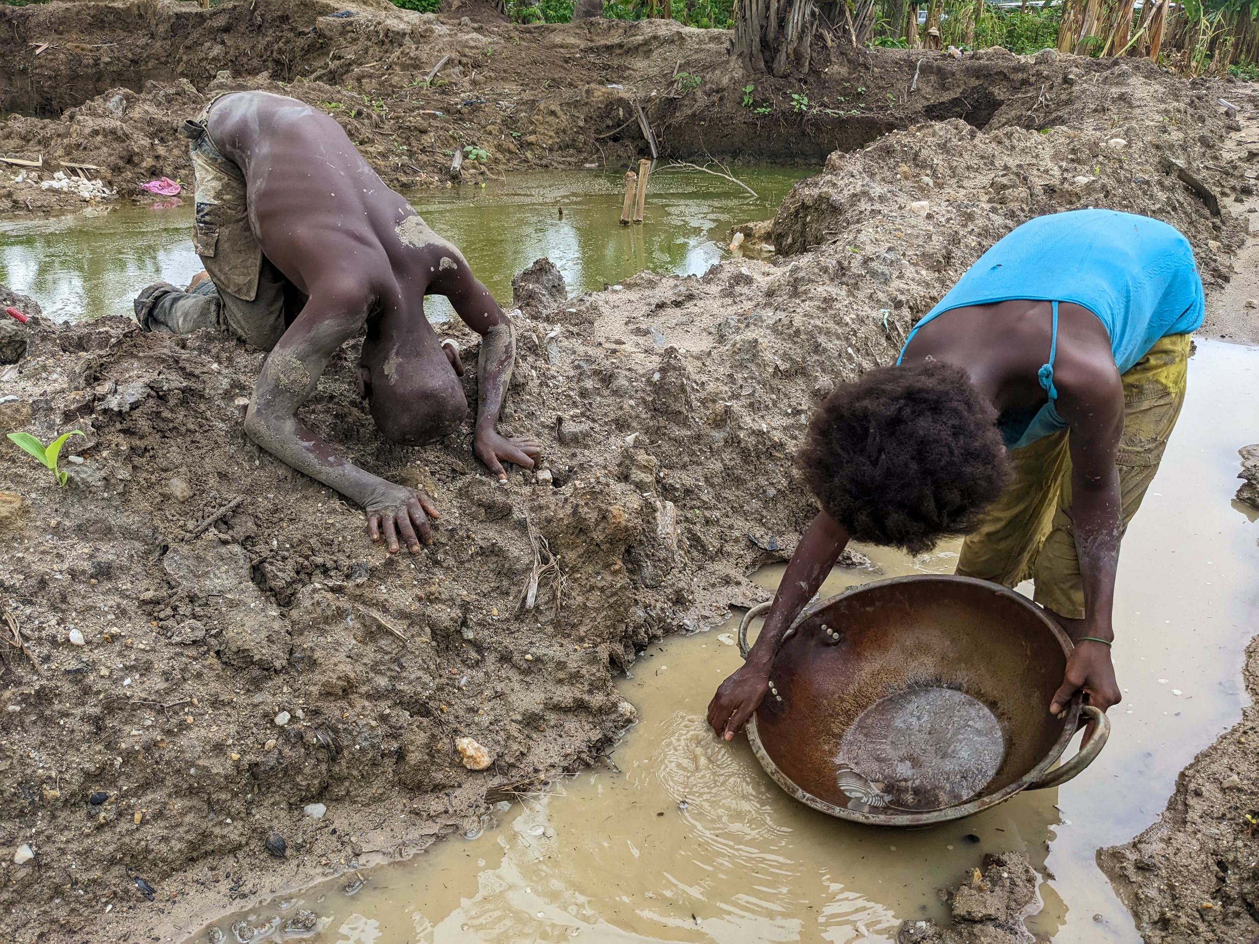 A young boy and young girl look for gold particles in a small mining site in Iperindo, Osun state. [Eromo Egbejule/Al Jazeera]