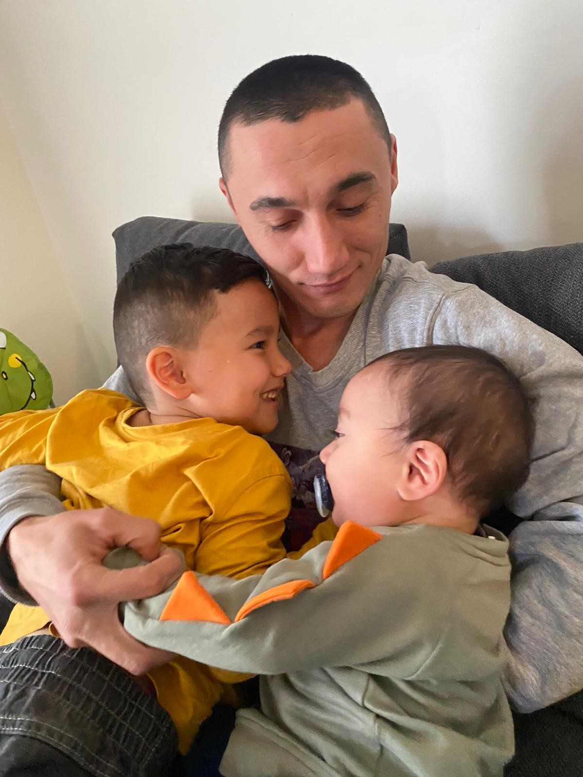 Sadam Abdusalam with his two sons on his lap.