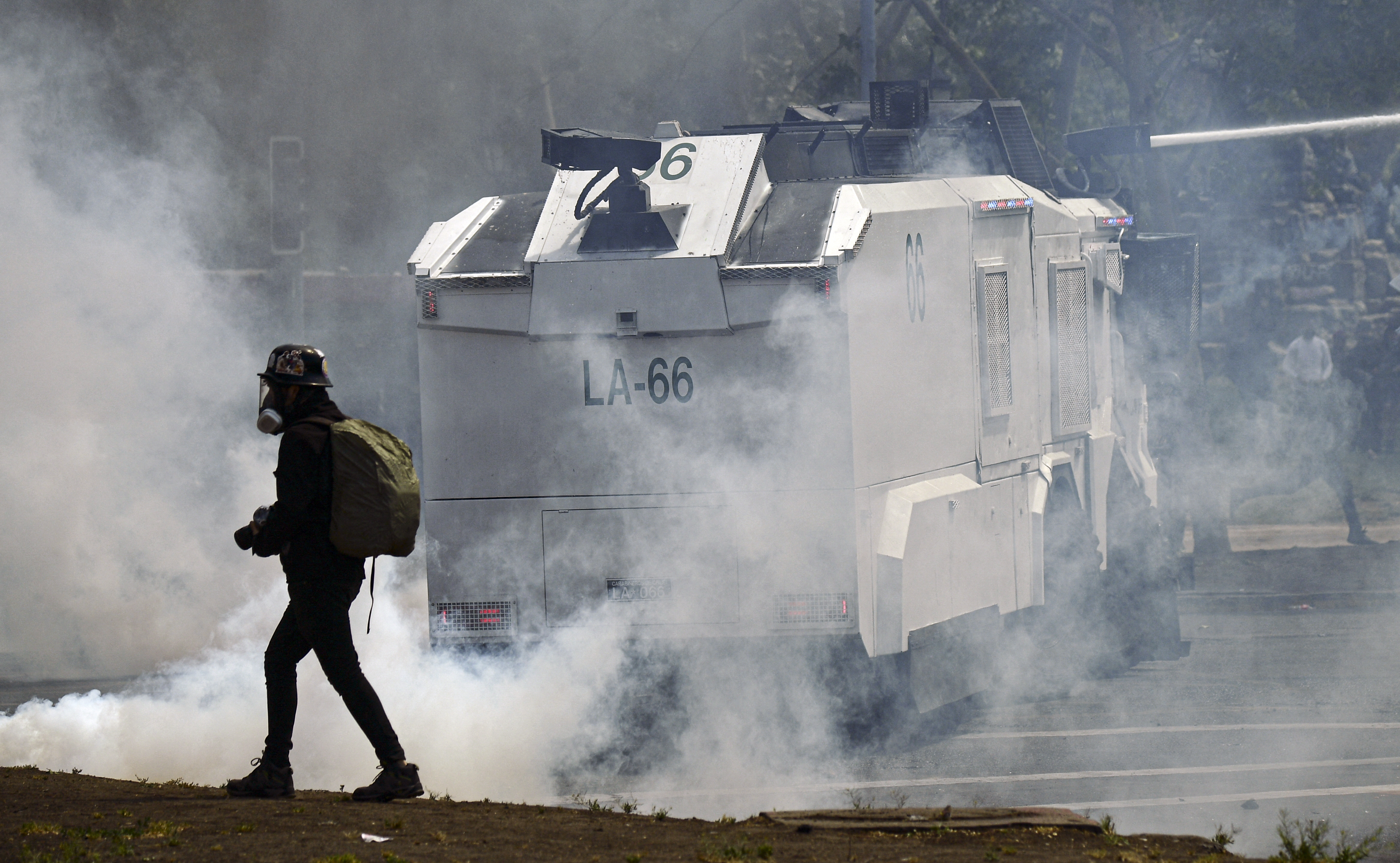 Smoke envelops protester walking past police vehicle