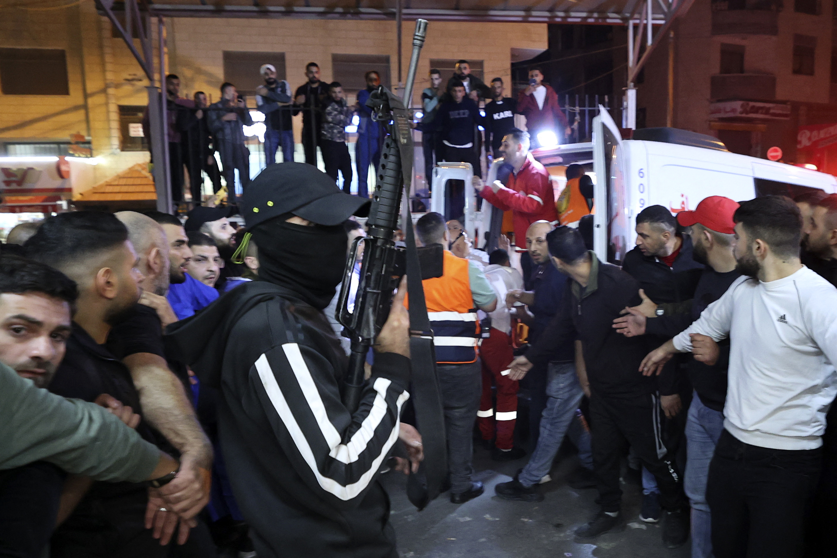A member of The Lions' Den group escort injured men into a hospital after clashes with Israeli forces in Nablus, in the occupied West Bank, early on October 25