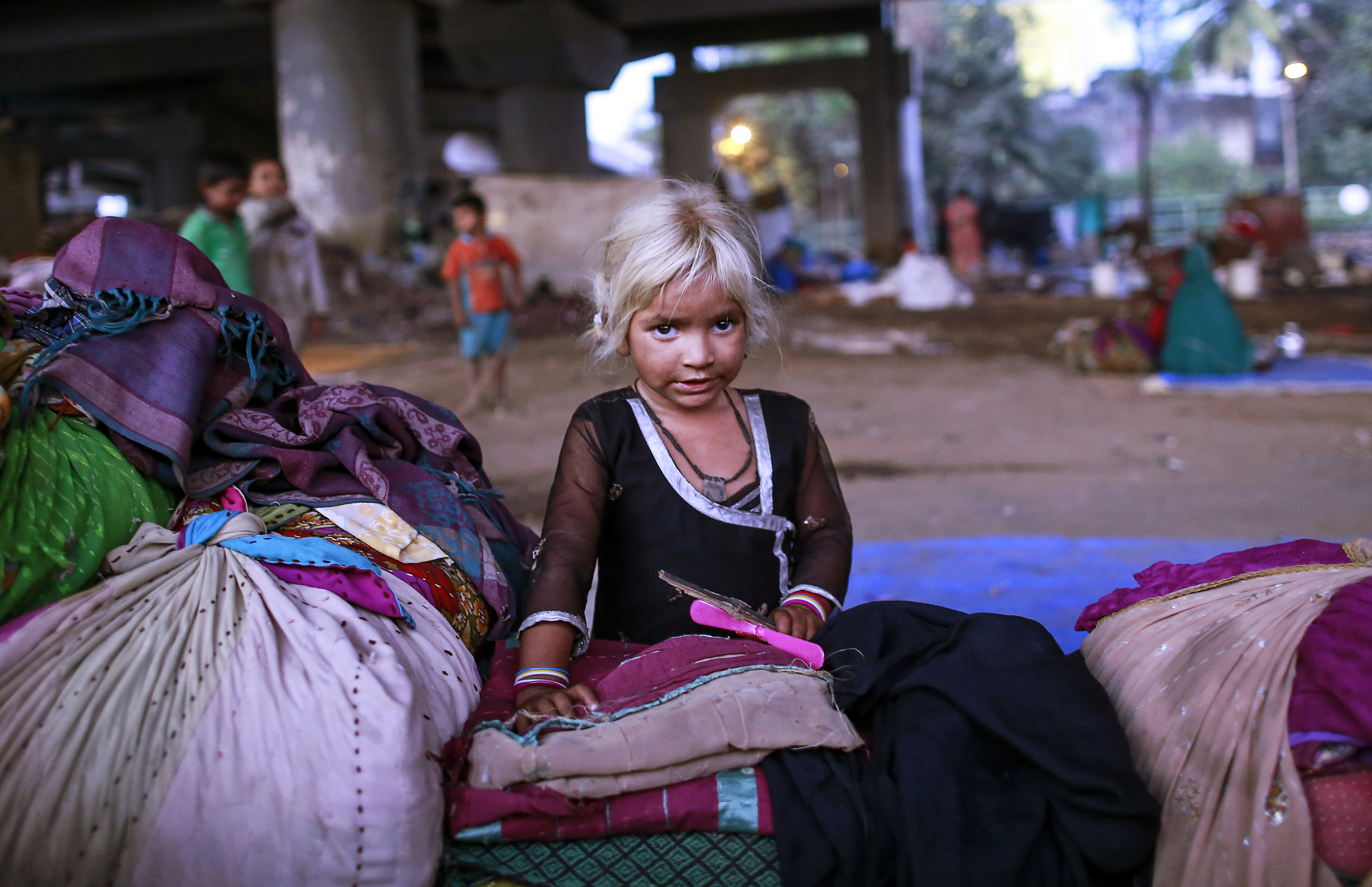Five-year-old Nasreen rests with her family's belongings as she plays under a flyover in Mumbai January 19, 2015