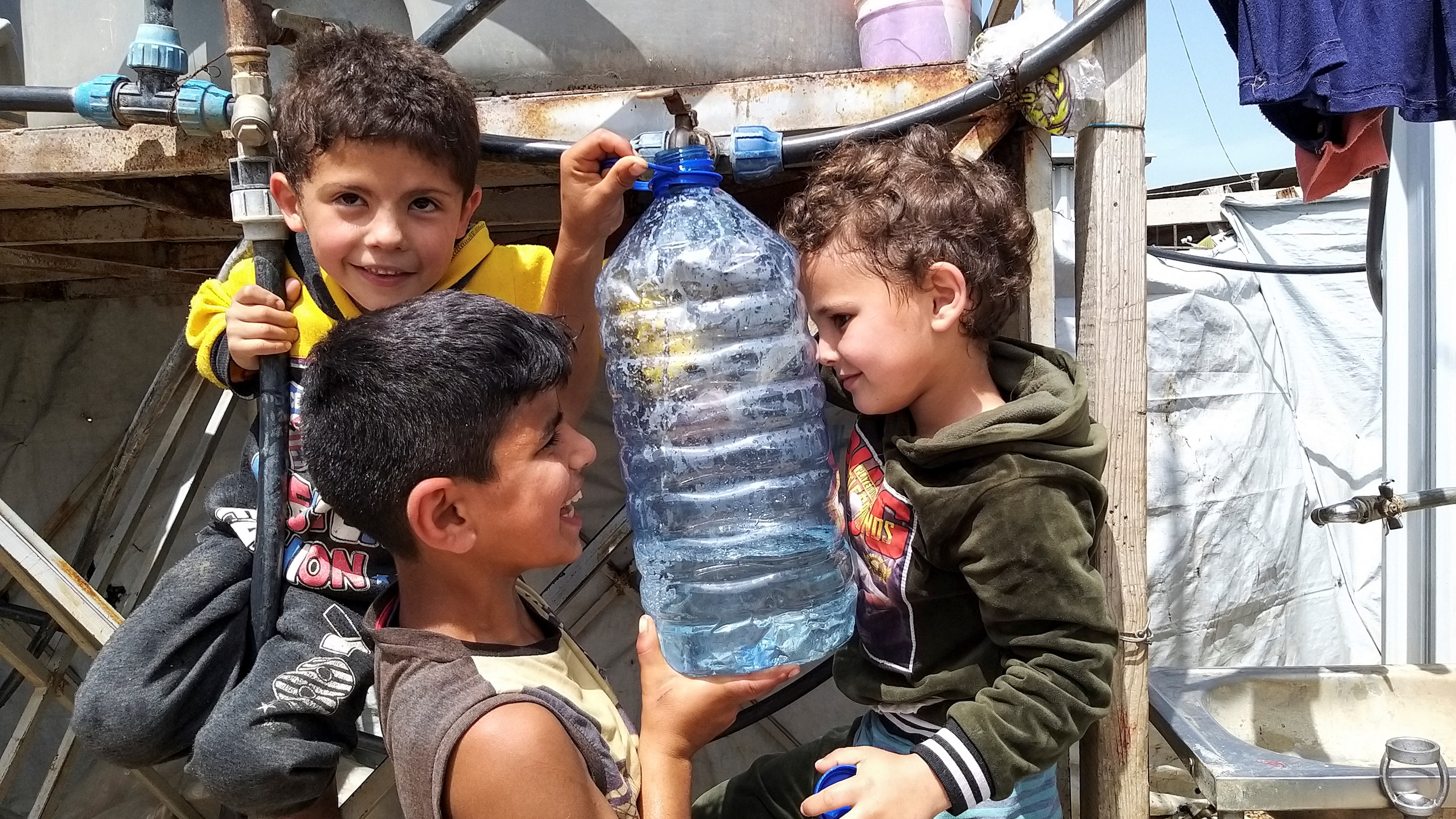 A Syrian refugee child holds a water bottle at an informal tented settlement in Akkar, Lebanon.