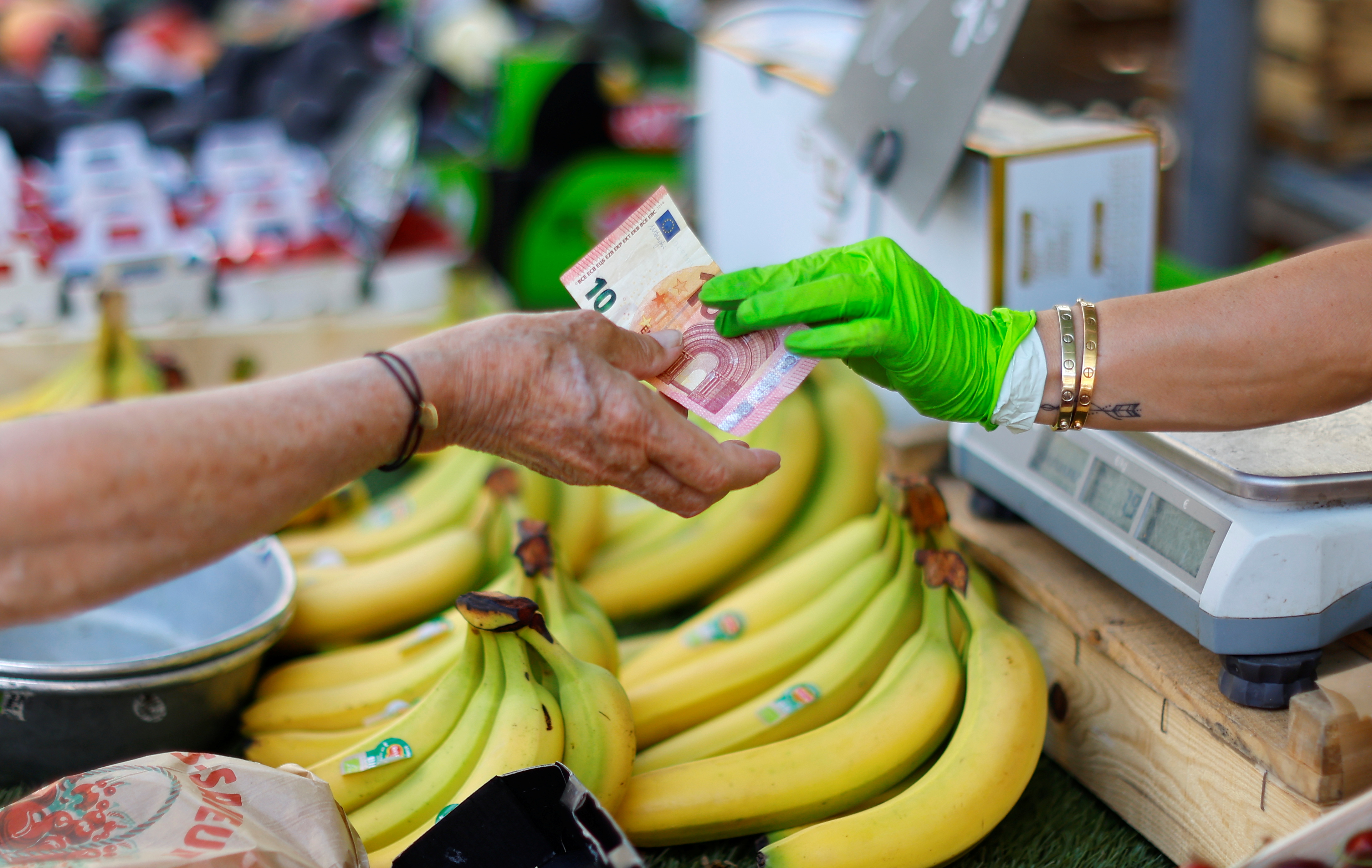 A shopper pays with a ten Euro bank note at a local market in Nice, France