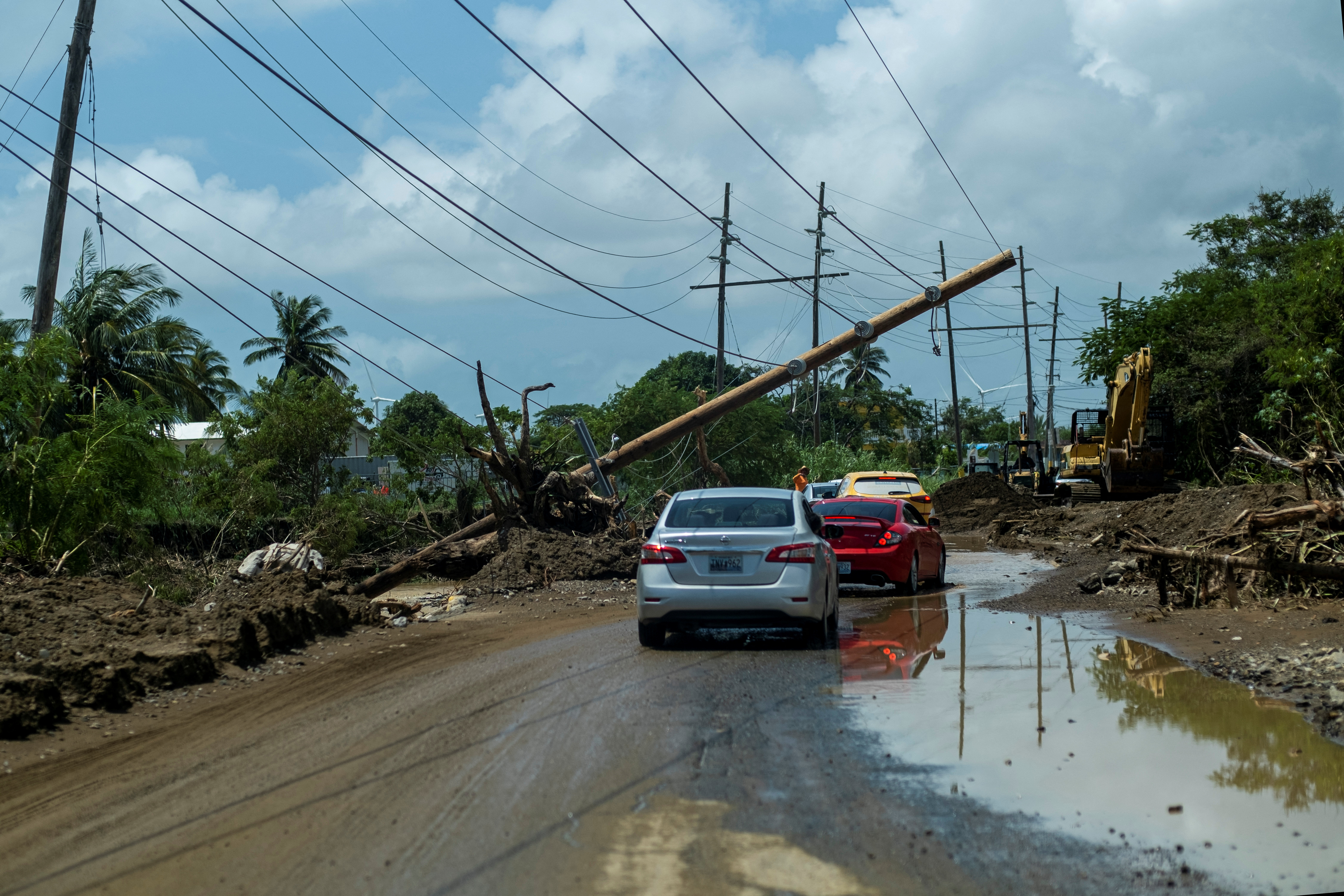 Cars drive under a downed power pole in the aftermath of Hurricane Fiona in Santa Isabel, Puerto Rico September 21, 2022.