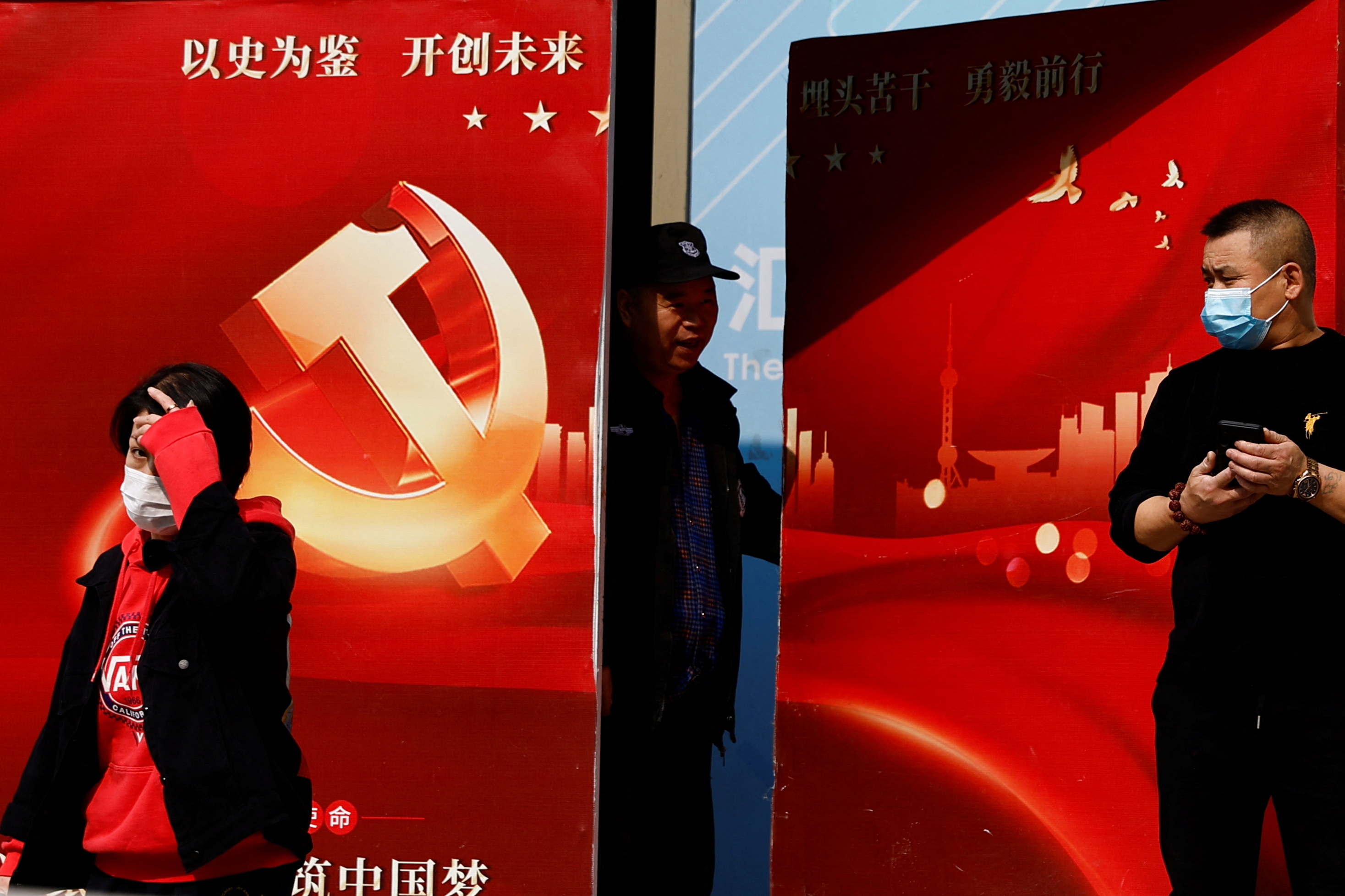 A security guard opens a door attached with a poster welcoming the 20th National Congress of the Communist Party of China, in Beijing