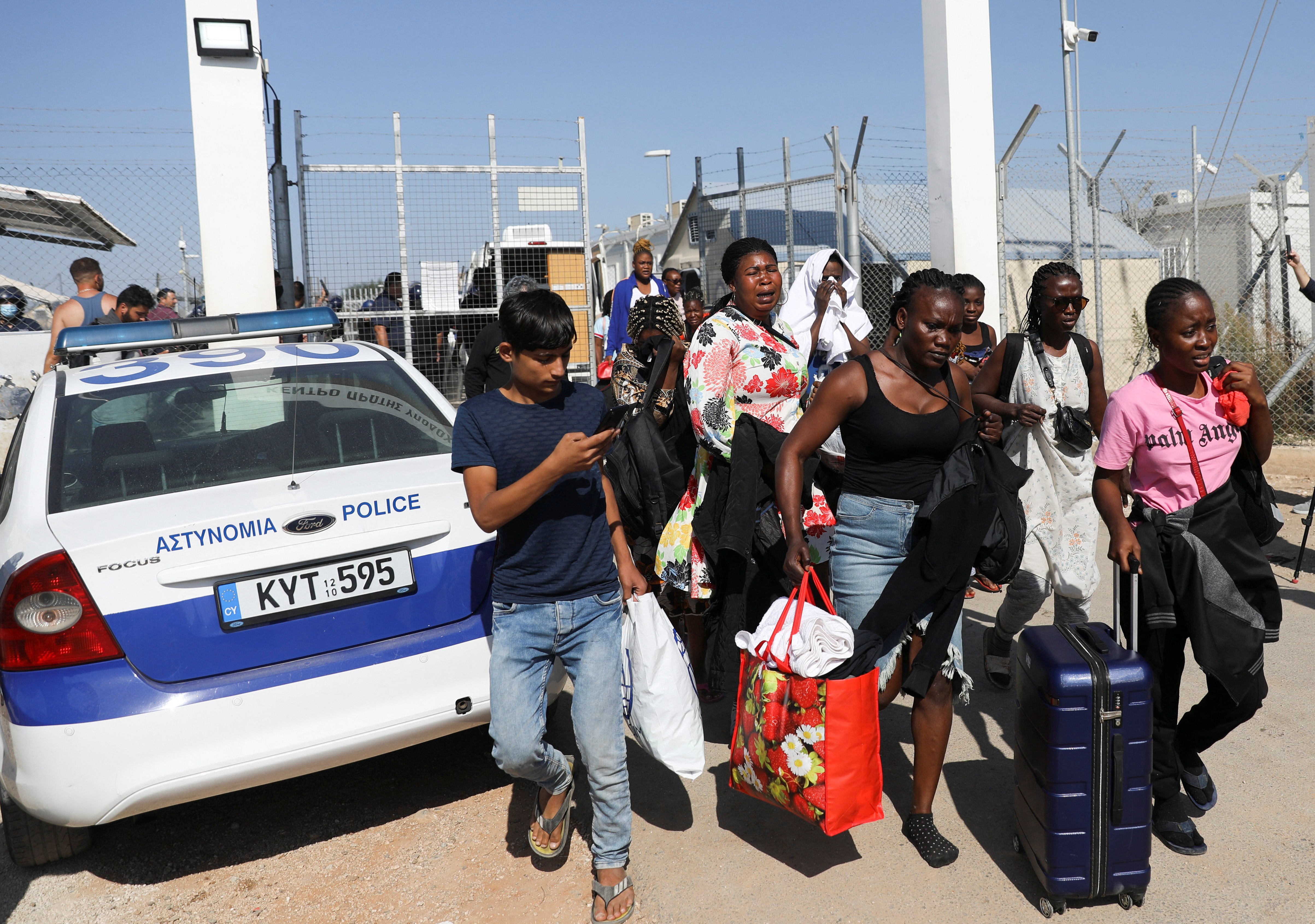 Migrants leave Pournara refugee camp during clashes in Kokkinotrimithia on the outskirts of Nicosia