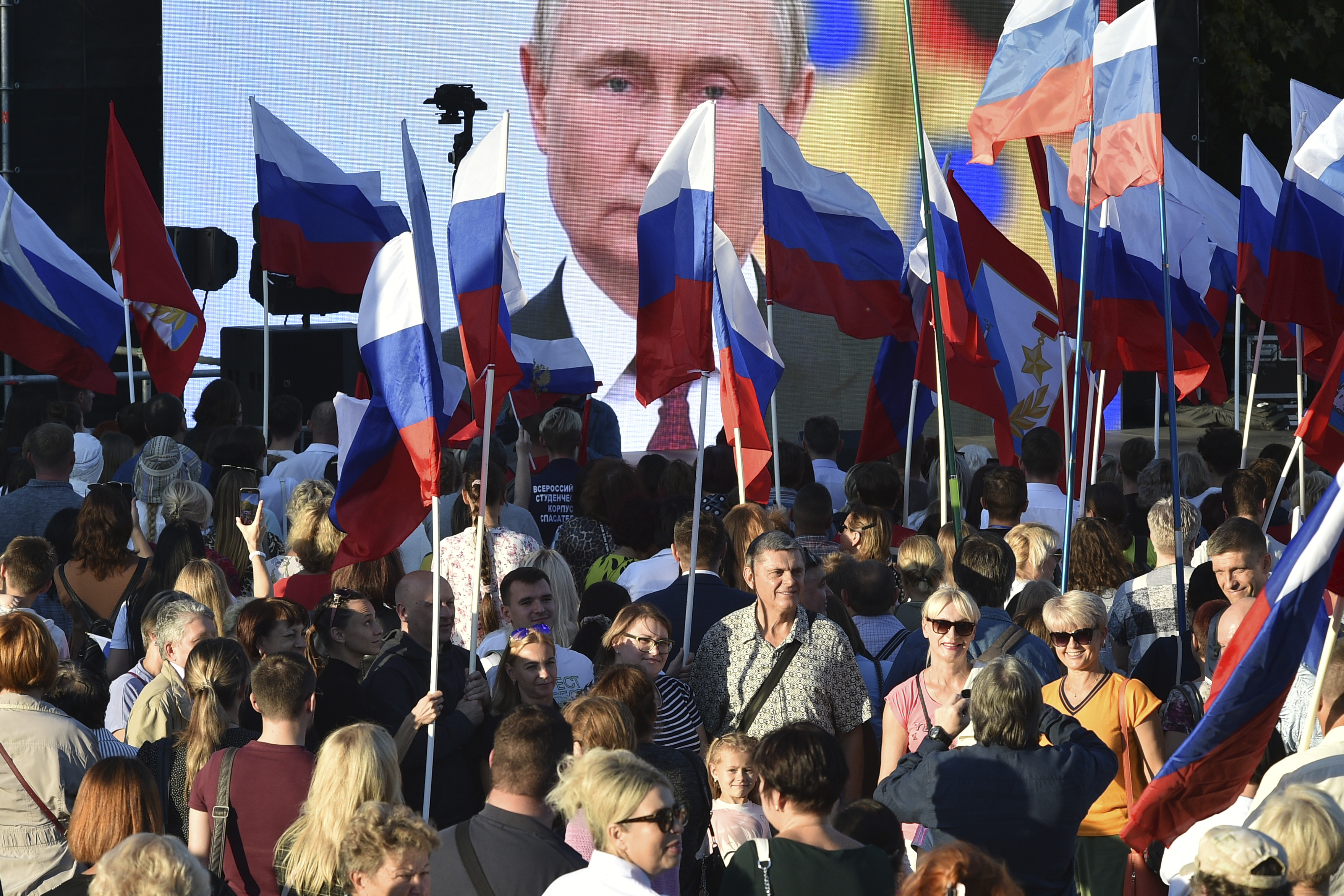 People gather in front of a large screen, to celebrate the incorporation of regions of Ukraine to join Russia.