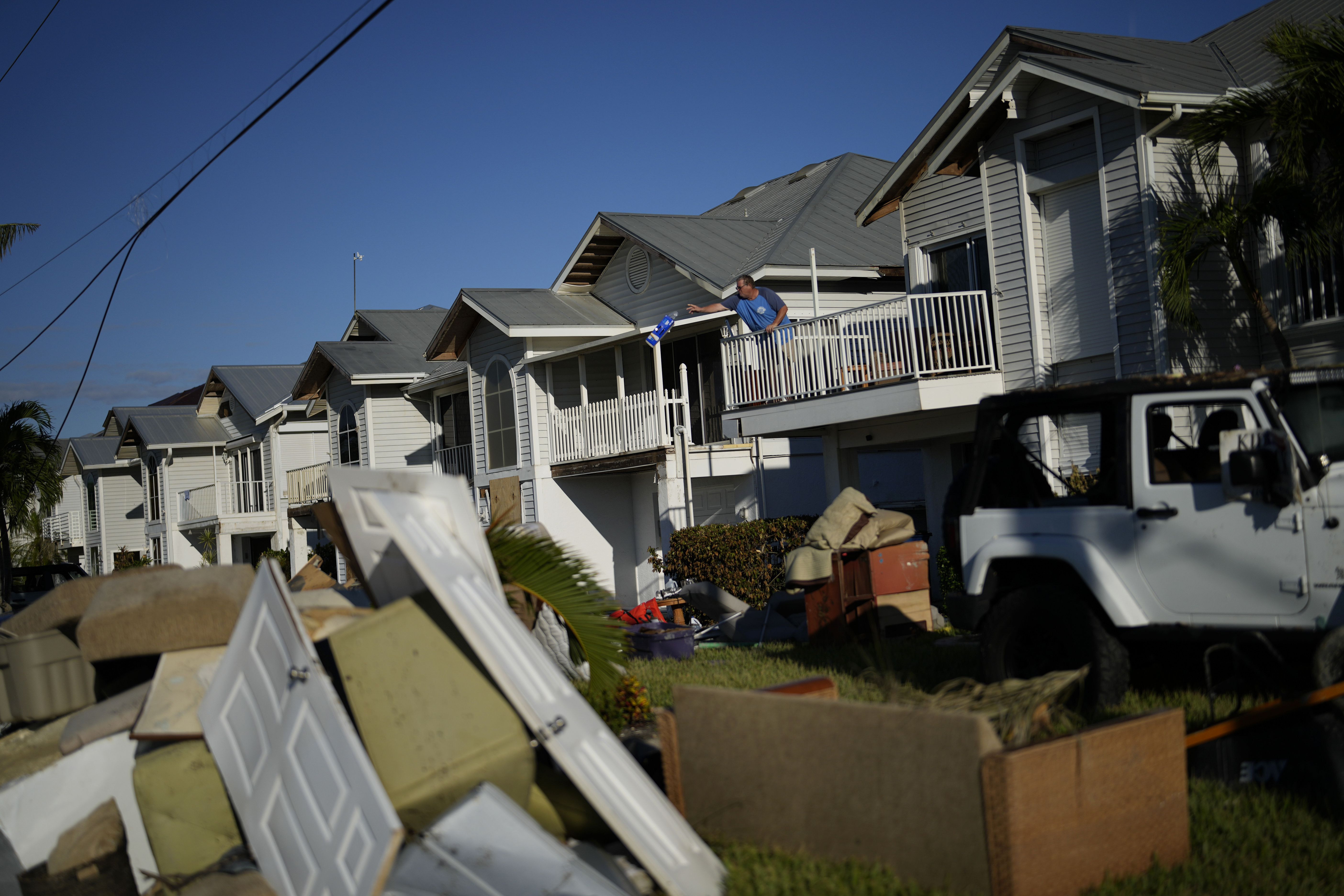 Snowbird Bob Fennessey of Montreal, Canada, clears out storm-damaged items from his condo, as ruined furniture and a car from his neighbors' vacation home sits on the lawn, after storm surge filled the first story of their houses during the passage of Hurricane Ian