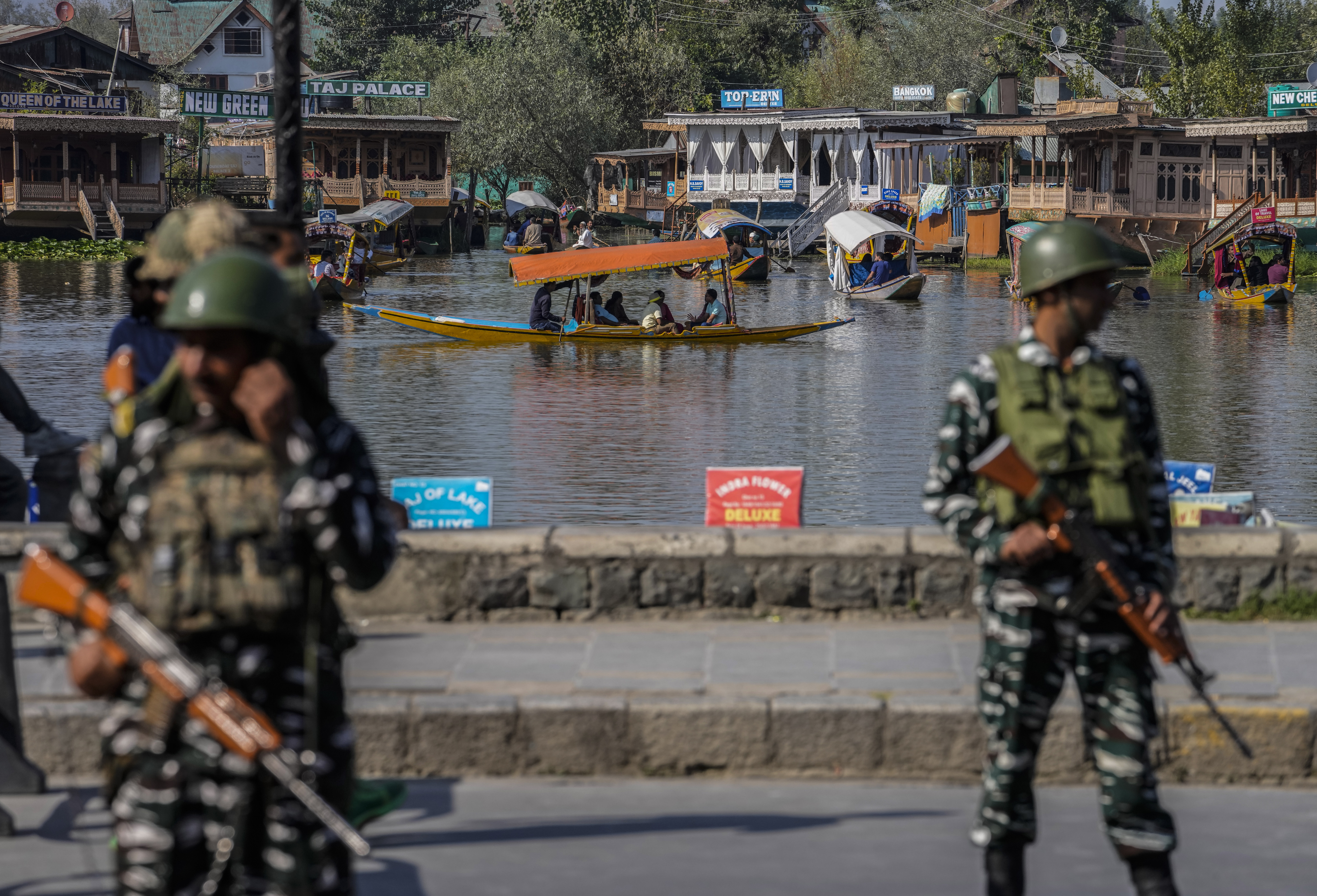 Indian paramilitary soldiers guard as tourists pass in a boat