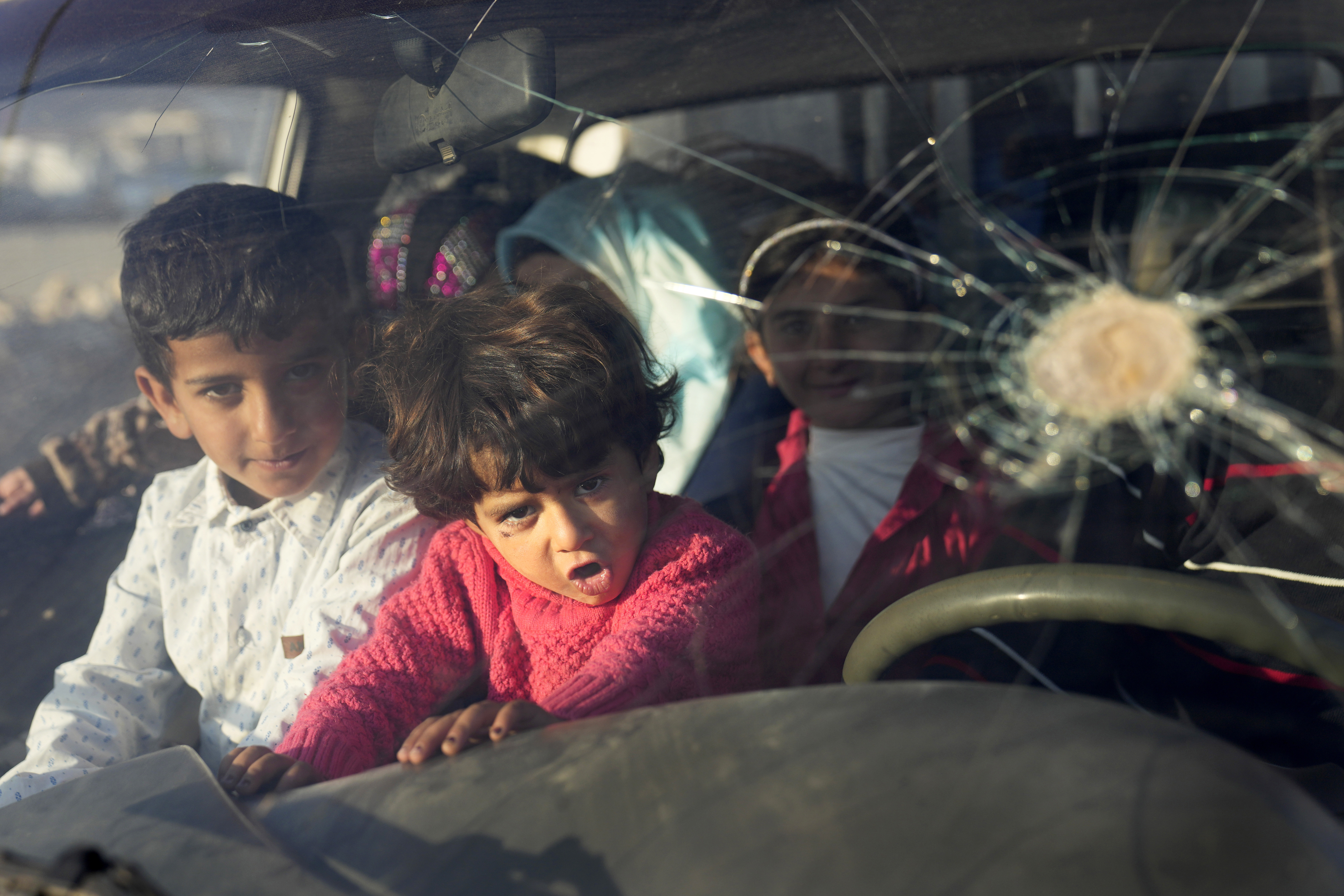Syrian refugee children sit inside a car with their family