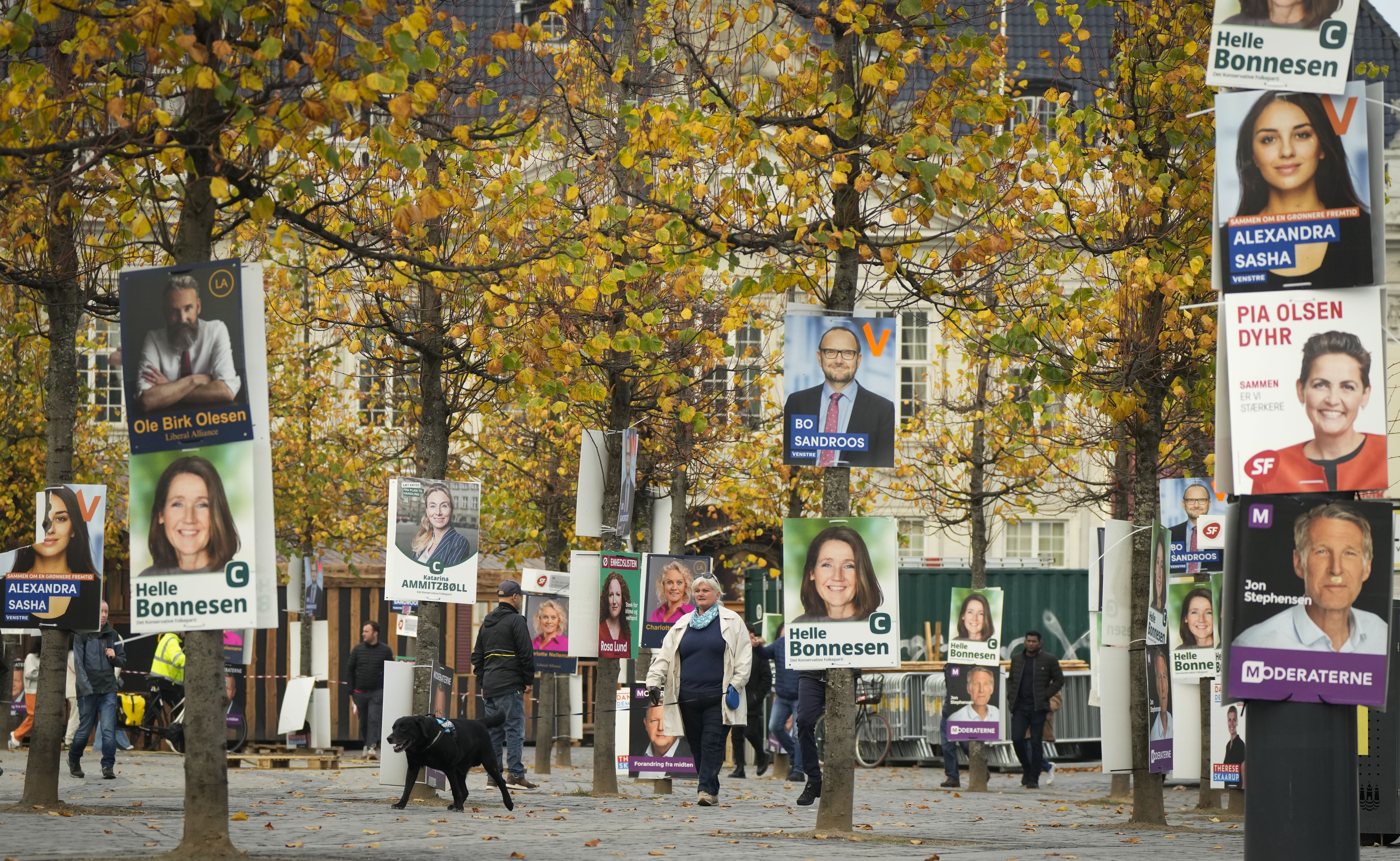 People pass by election campaign posters in Copenhagen, Denmark, Sunday, Oct. 30, 2022, ahead of the general election scheduled for Nov. 1, 2022. Denmark's election on Tuesday is expected to change its political landscape, with new parties hoping to enter parliament and others seeing their support dwindle. A former prime minister who left his party to create a new one this year could end up as a kingmaker, with his votes being needed to form a new government. (AP Photo/Sergei Grits)