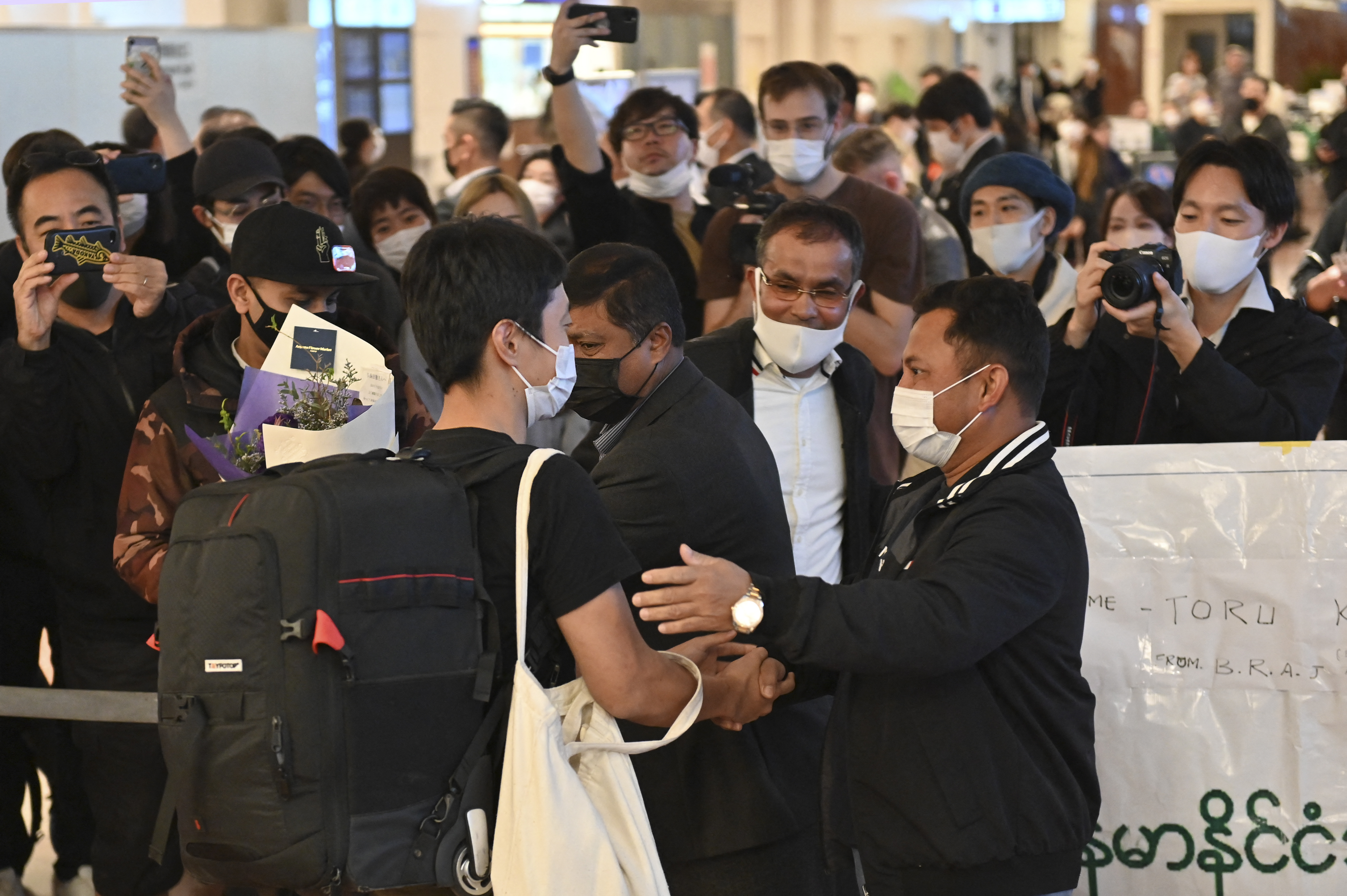 Japanese journalist Toru Kubota with a black backpack welcomed by dozens of supporters looking happy at Haneda airport in Tokyo