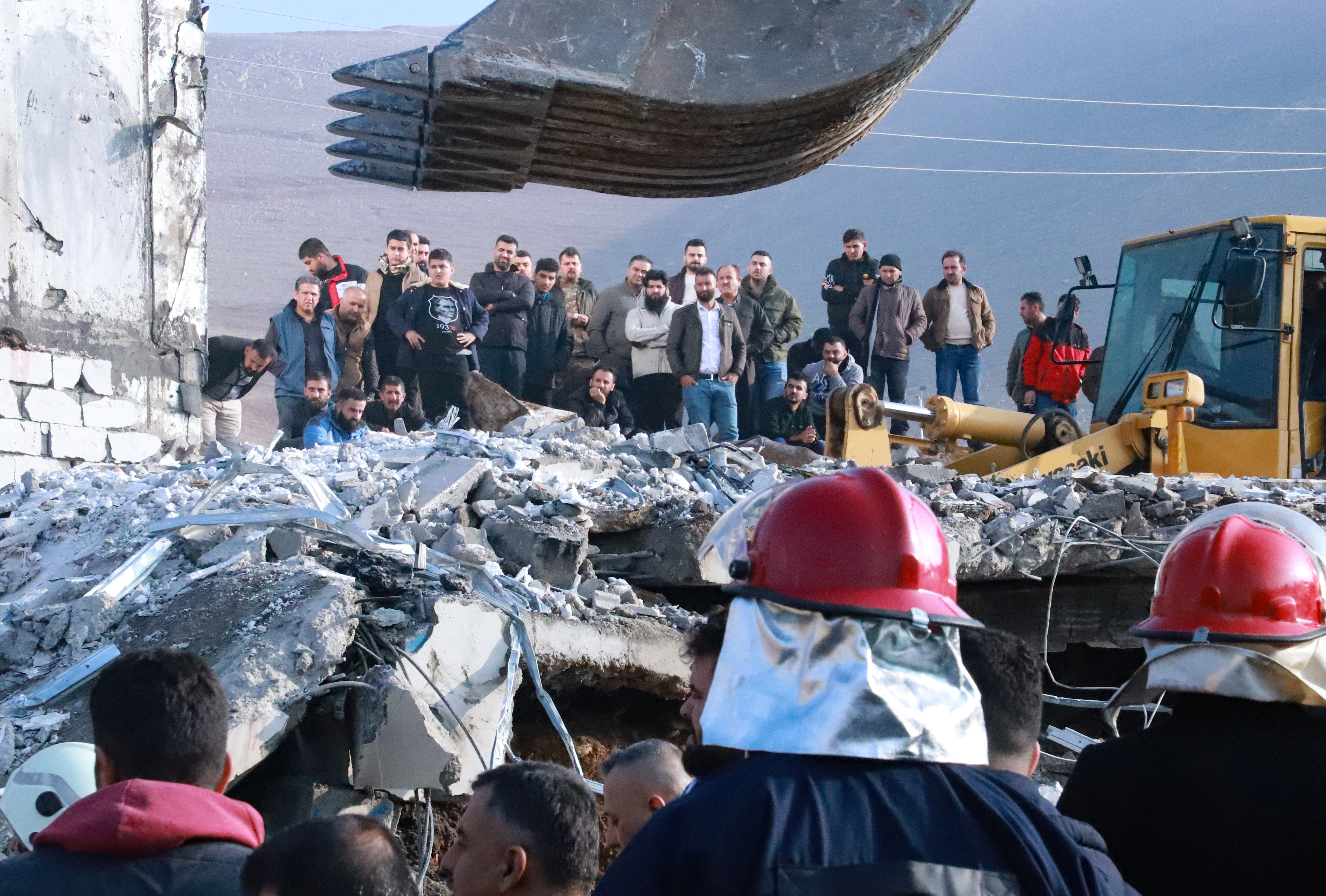 People gather as firefighters search for victims and survivors under the rubble of a building which collapsed after gas tank exploded, in the northern Iraqi city of Suleimaniyah, on November 18, 2022. - The search for victims trapped under the rubble continues, after at least 11 people were killed, local authorities said. (Photo by Shwan MOHAMMED / AFP)