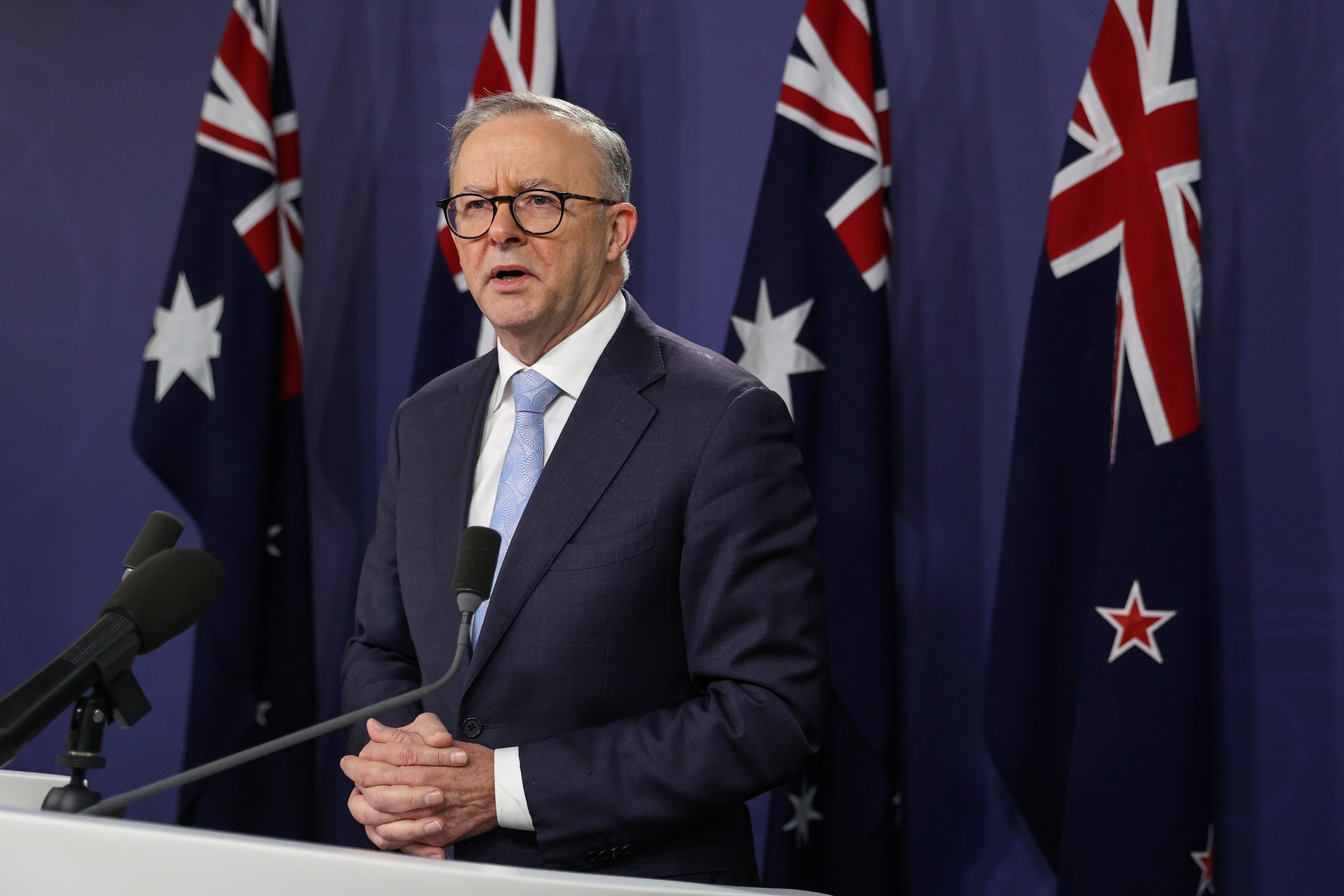 Australian Prime Minister Anthony Albanese at podium with Australian flags behind him
