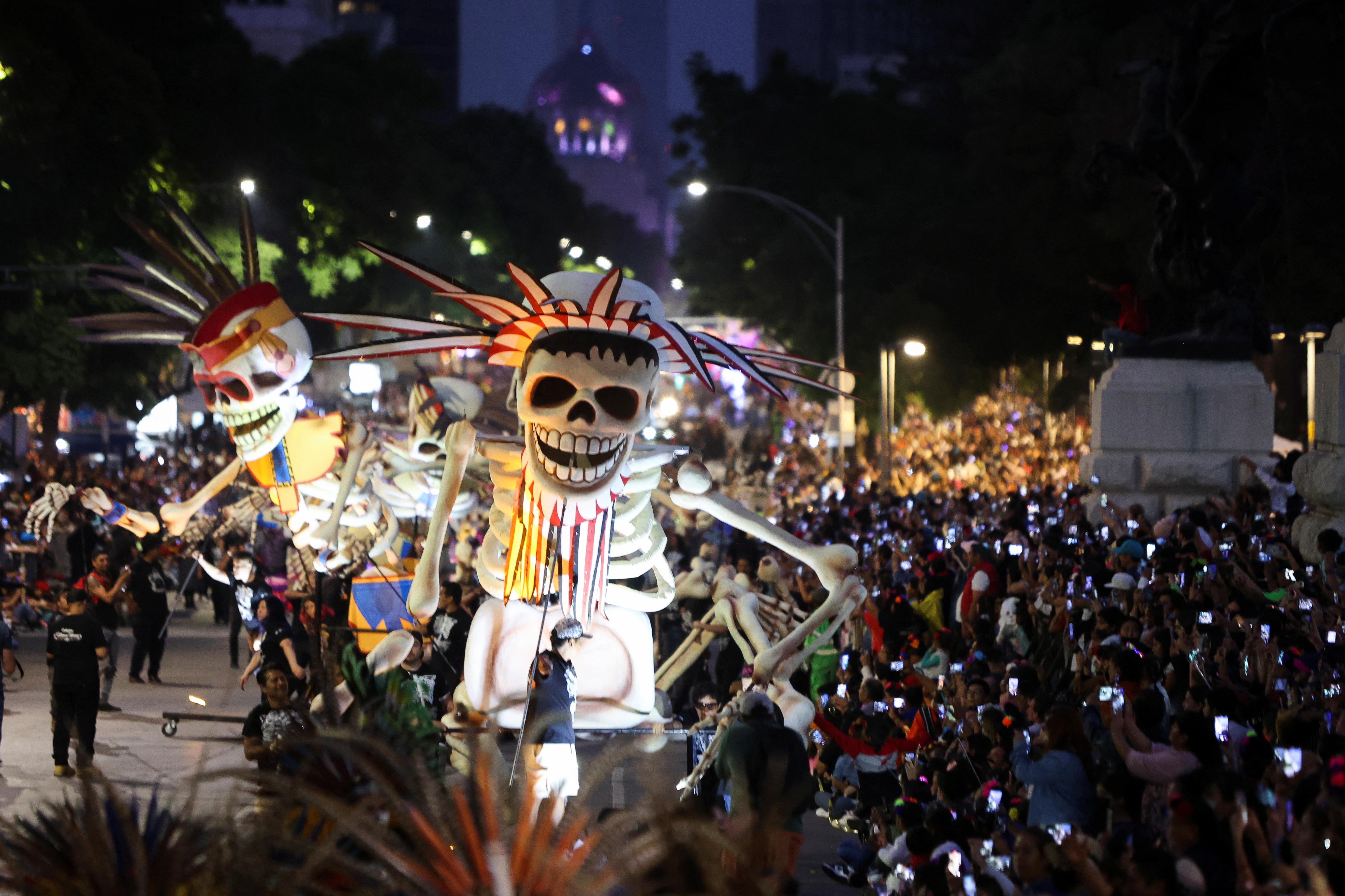 People look at giant skeletons during the Day of the Dead parad