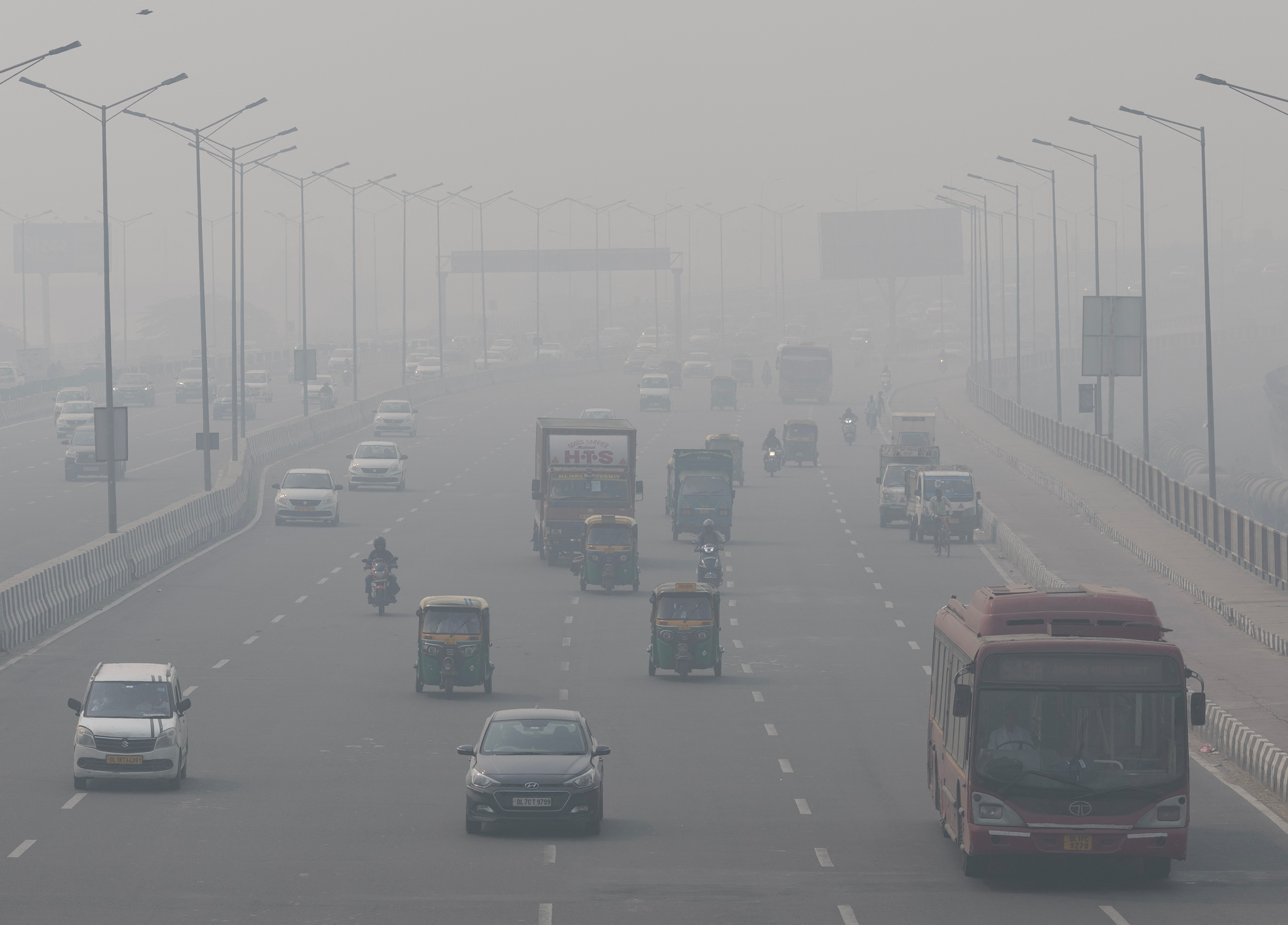 Vehicles on a Delhi road barely visible through smog