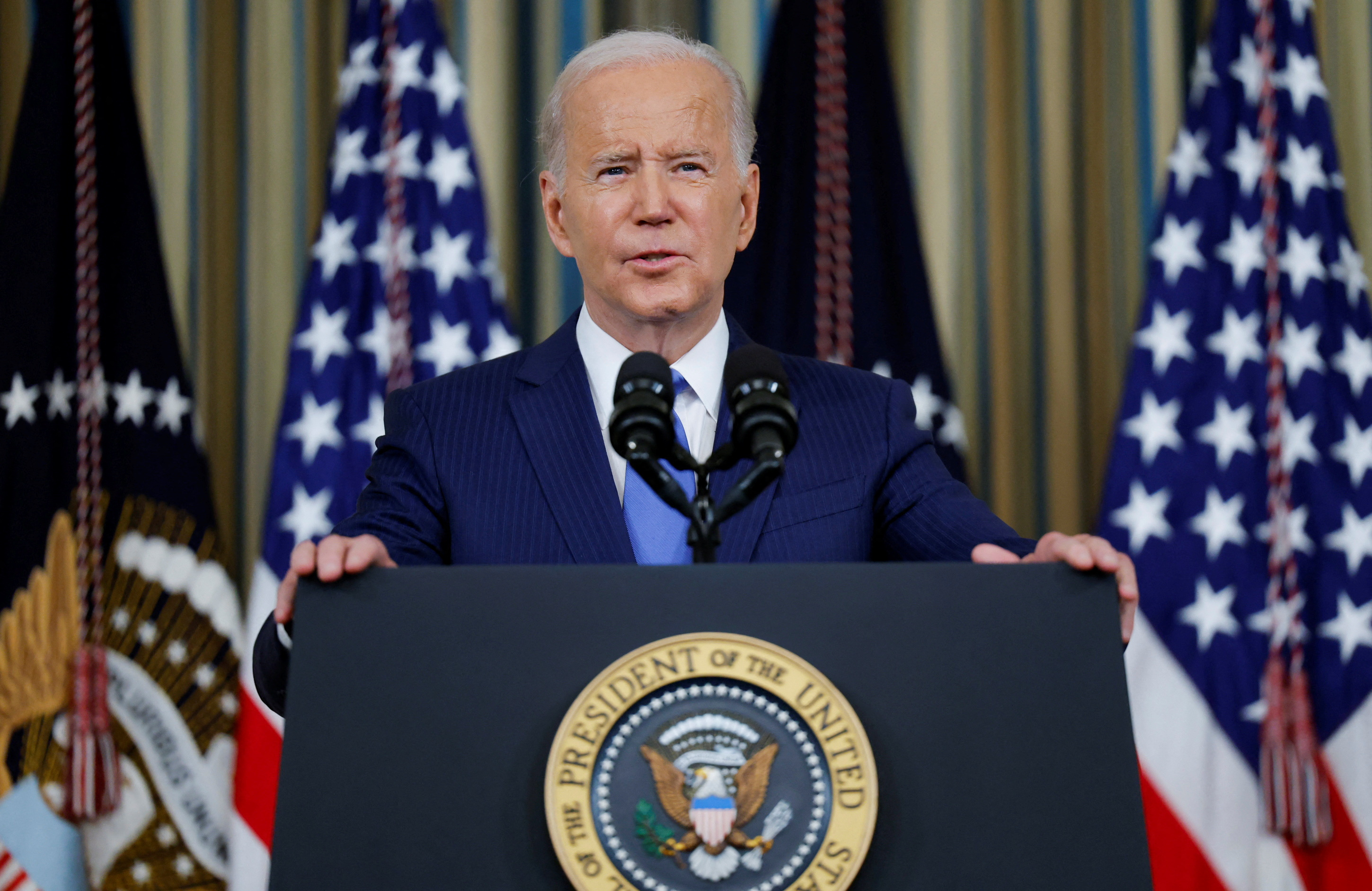 Biden behind Podium, with two US flags in background