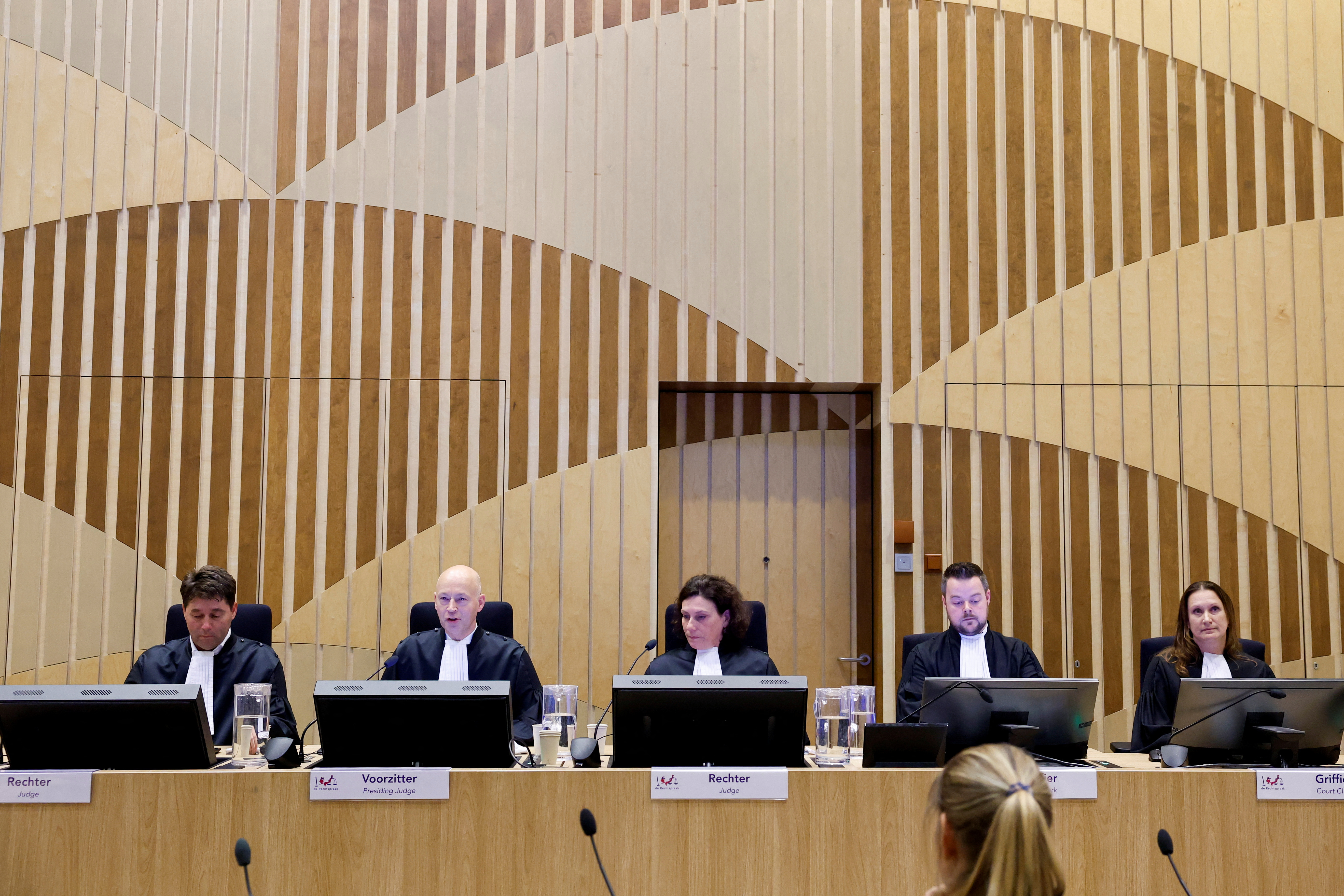 Judges sit in the courtroom as the Dutch court.