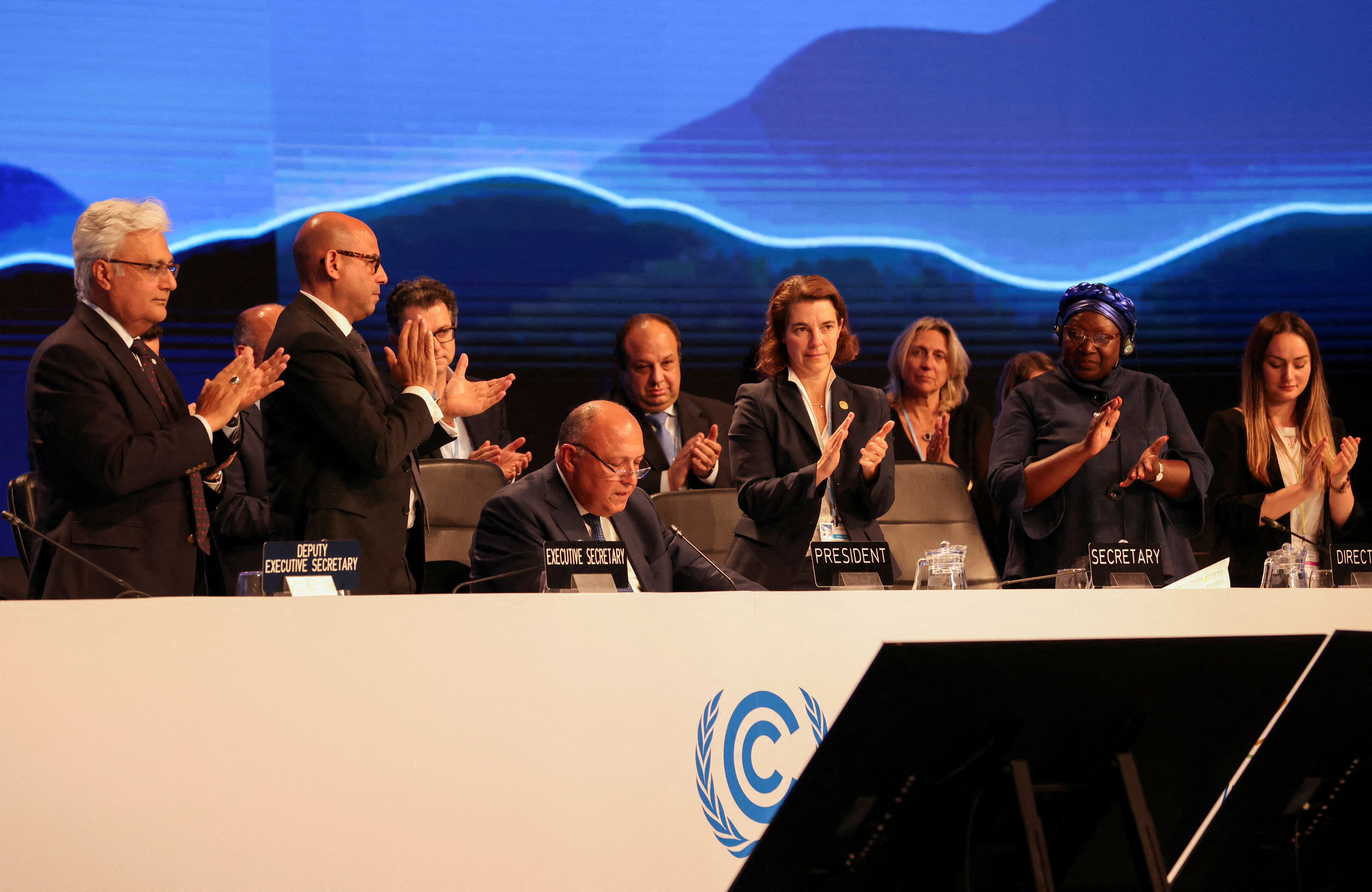 Delegates applaud as COP27 President Sameh Shoukry delivers a statement during the closing plenary at the COP27 climate summit in Red Sea resort of Sharm el-Sheikh