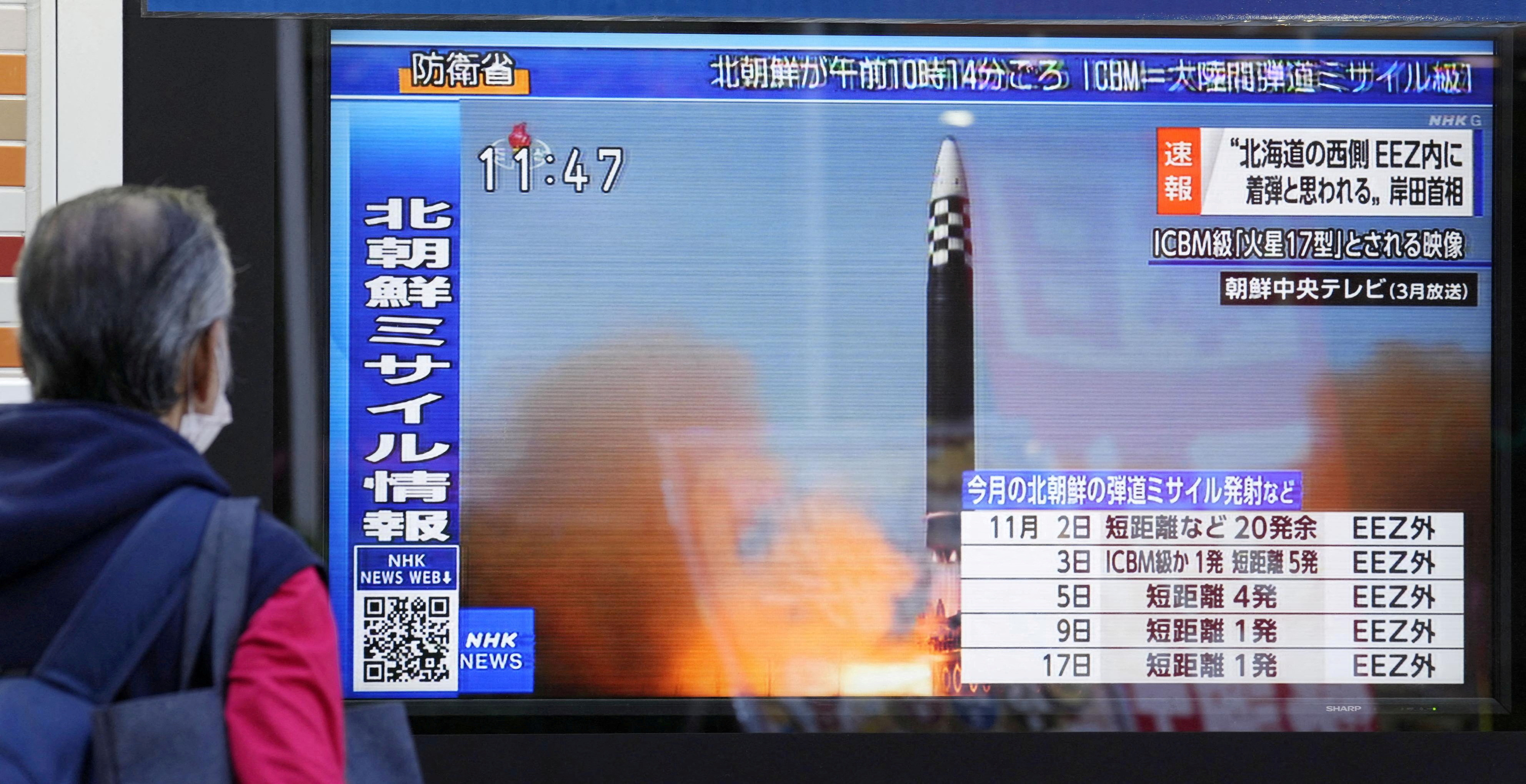 A passerby looks at a television screen showing a report about North Korea missile launch