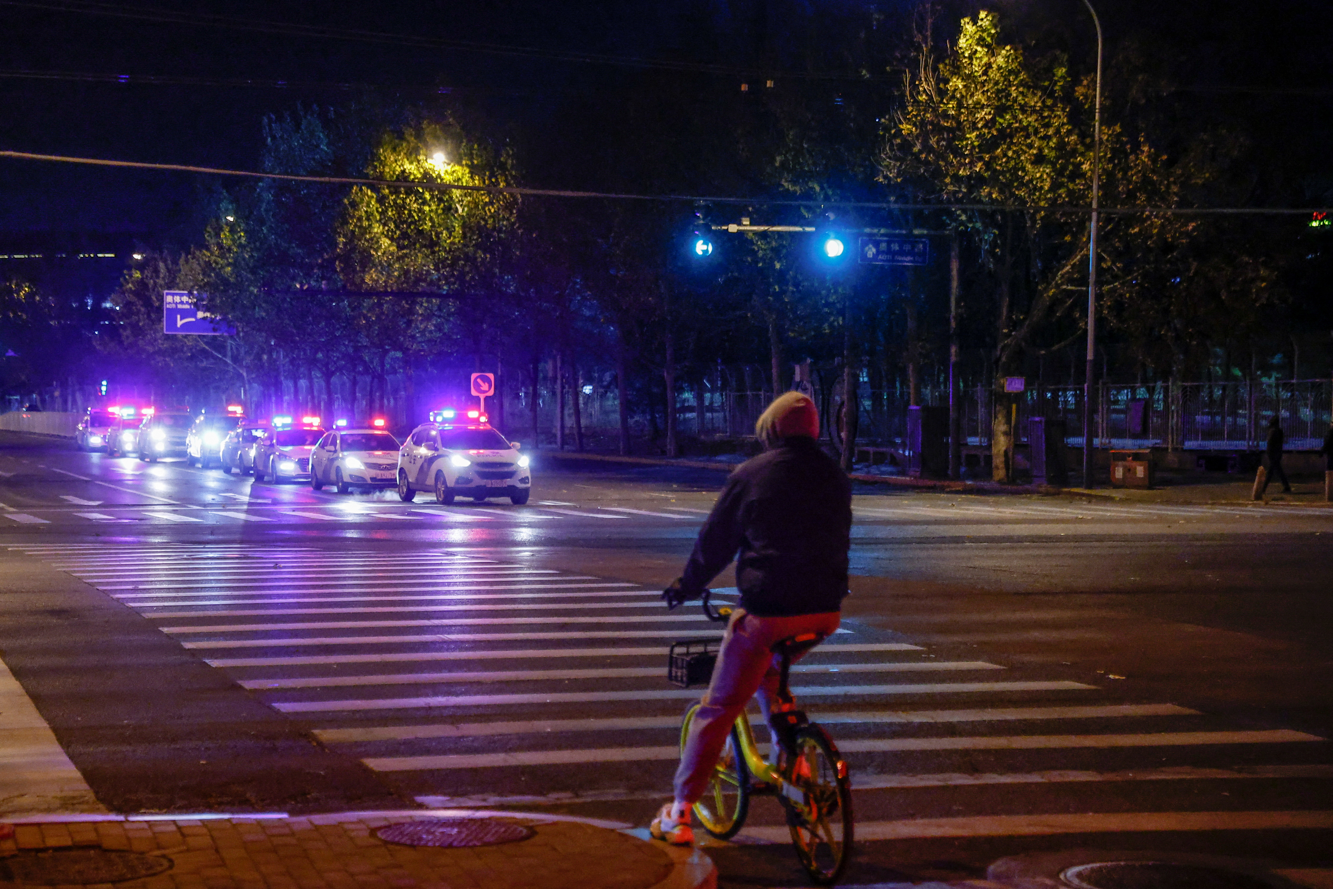 Police cars with lights flashing line up along a Beijing street where a protest was rumoured to take place.