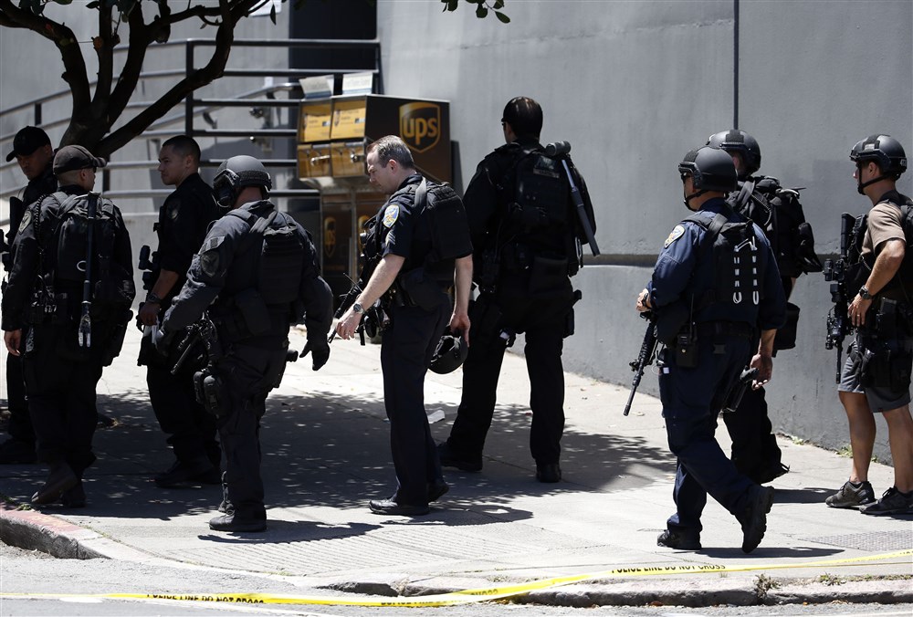 San Francisco SWAT officers in front of a building where a shooting has taken place. They are in black military-like uniforms and carrying weapons
