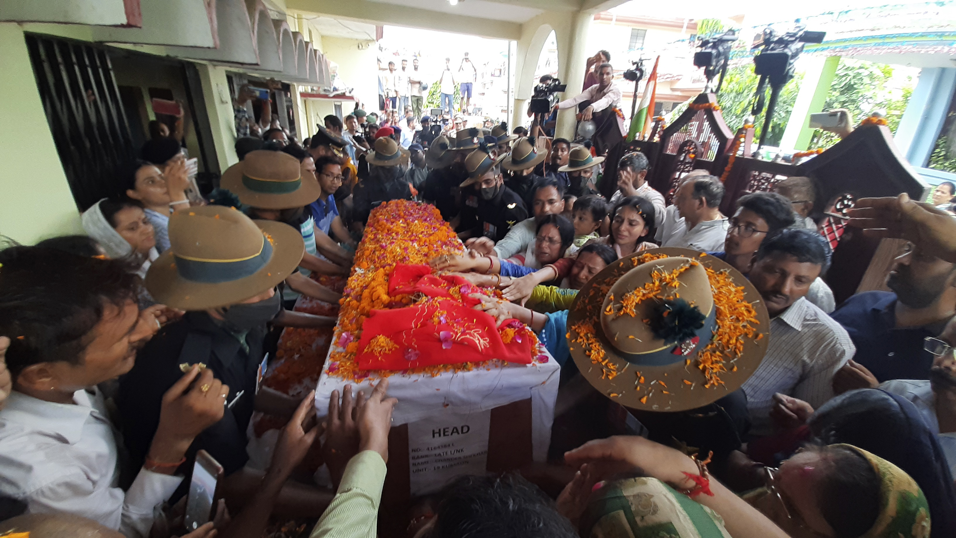 Family members stretch their arms out to touch the coffin containing the remains of Chandra Shekhar, an Indian army soldier who went missing 38 years ago, in Haldwani, 