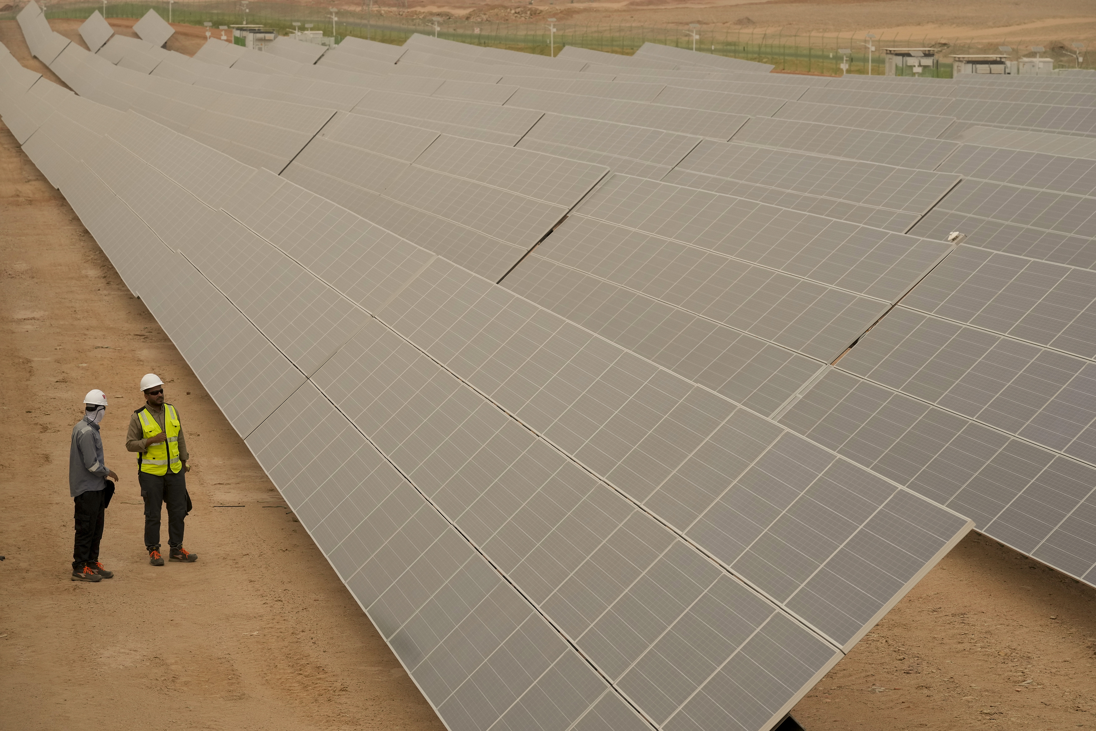 Engineers talk next to photovoltaic solar panels at Benban Solar Park, one of the world's largest solar power plant in the world, in Aswan.