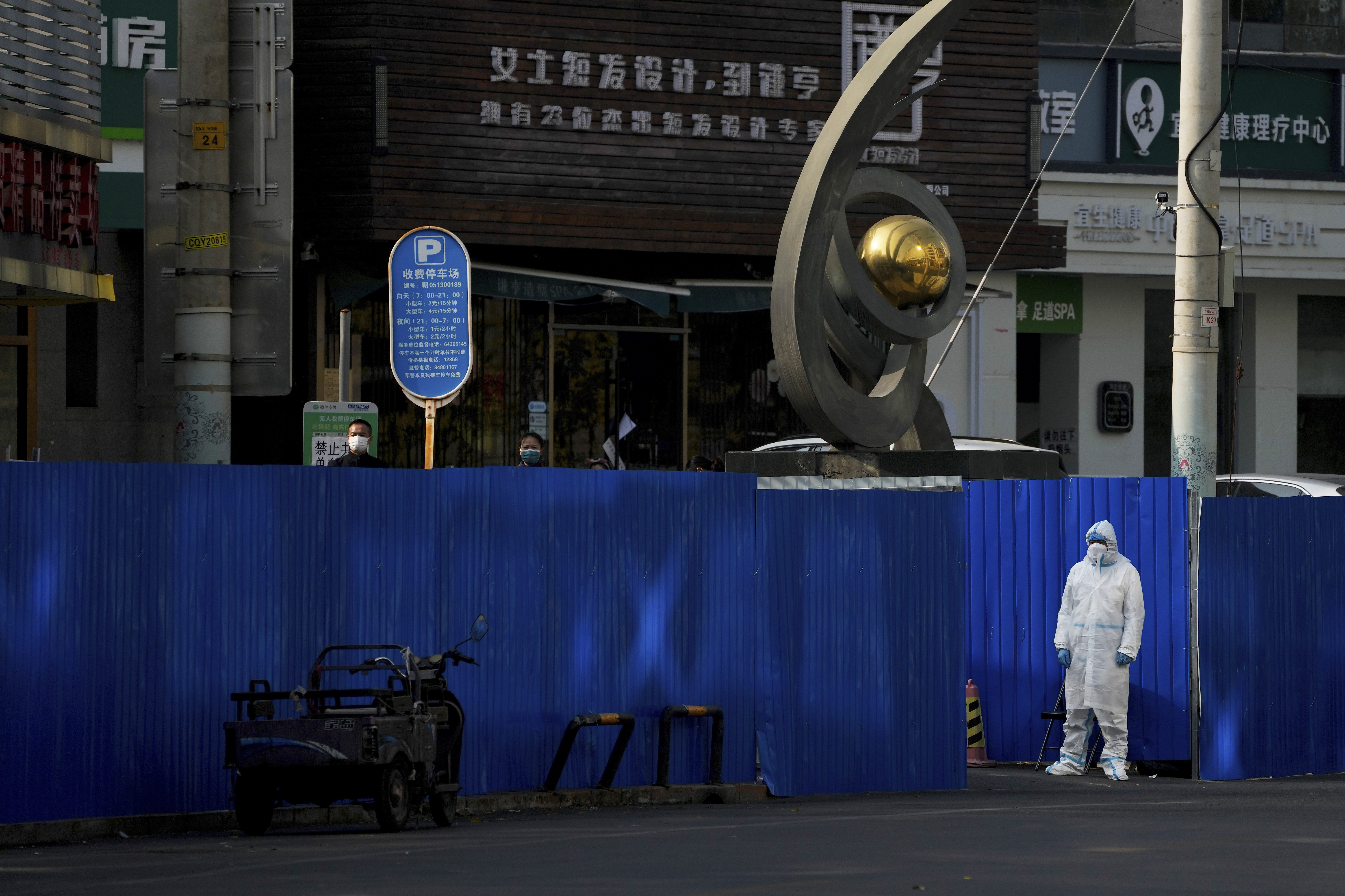 China worker in protective gear watches residents in face masks