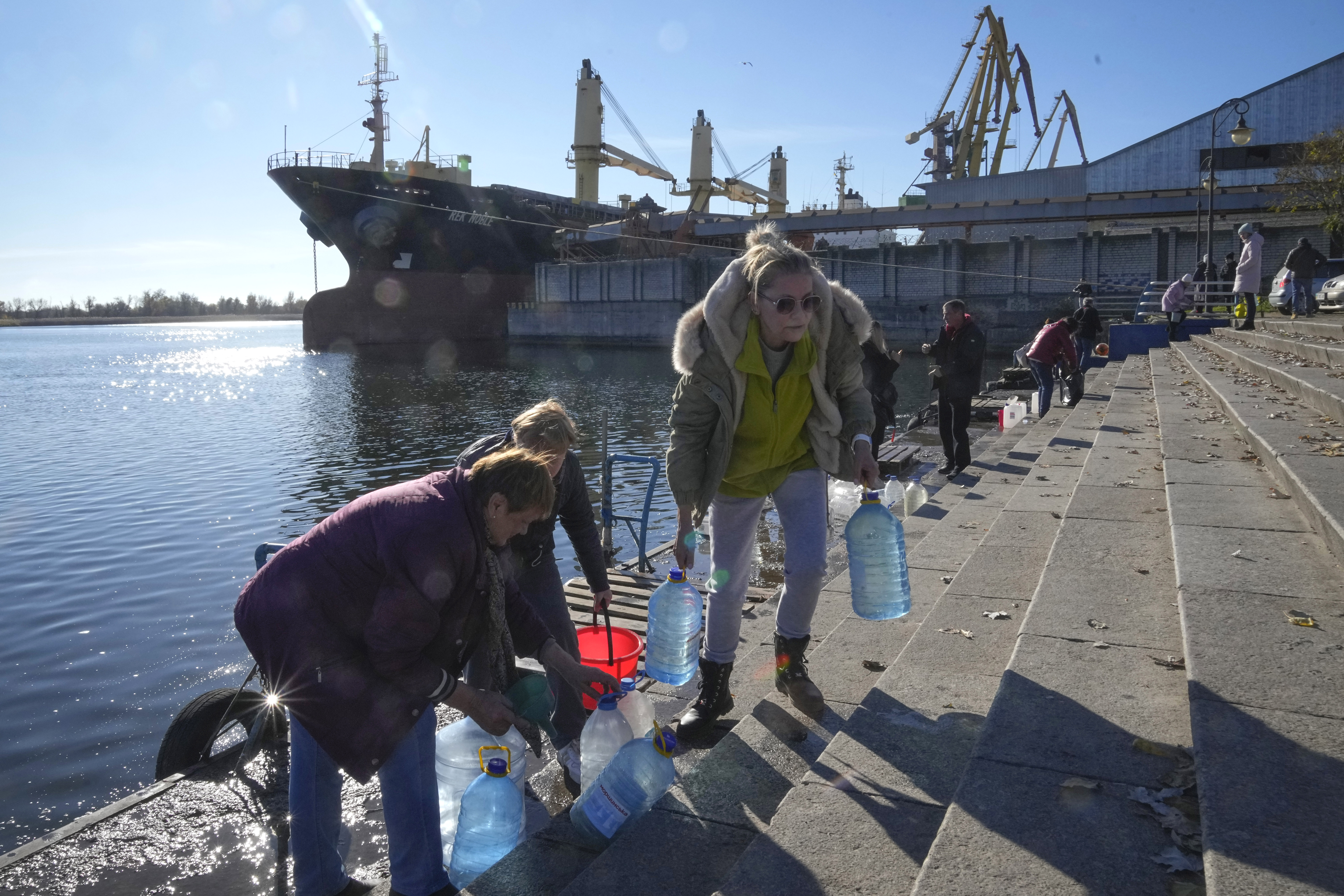 People collect water from a Dnipro river in Kherson.