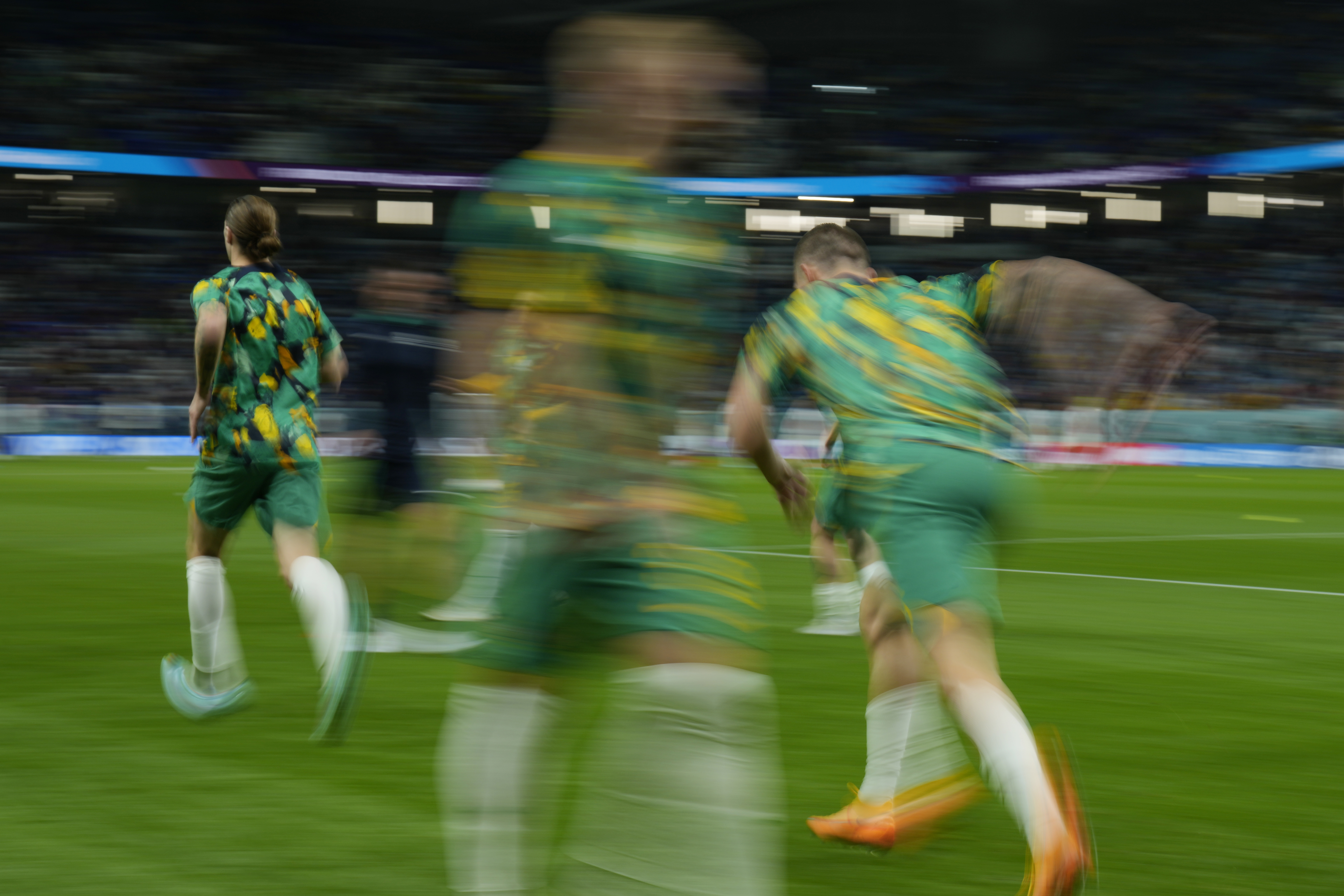 A motion blurred picture of three green-uniformed players from the back running onto the field