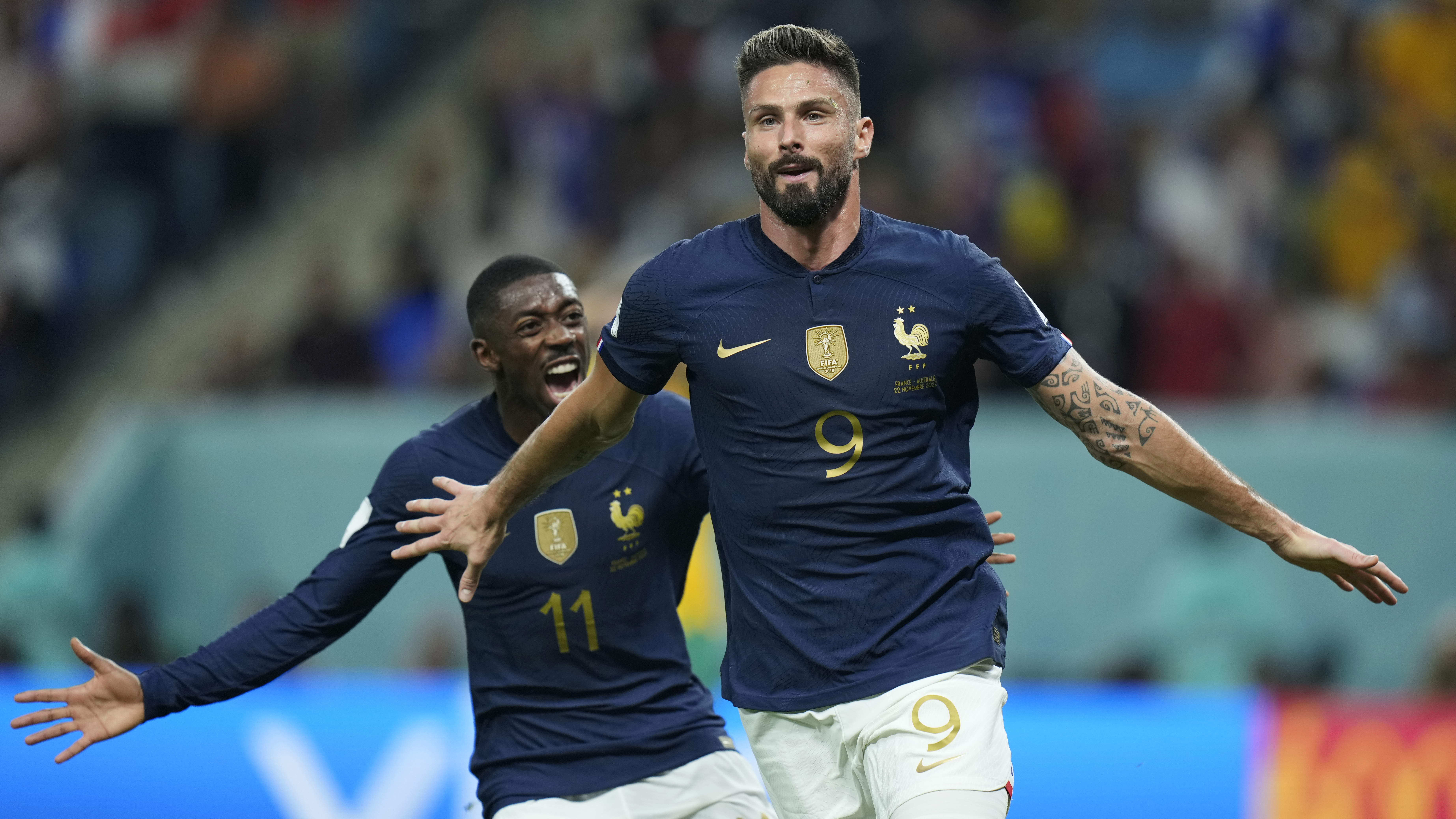 Giroud runs with his arms out as Dembele comes up behind him, smiling