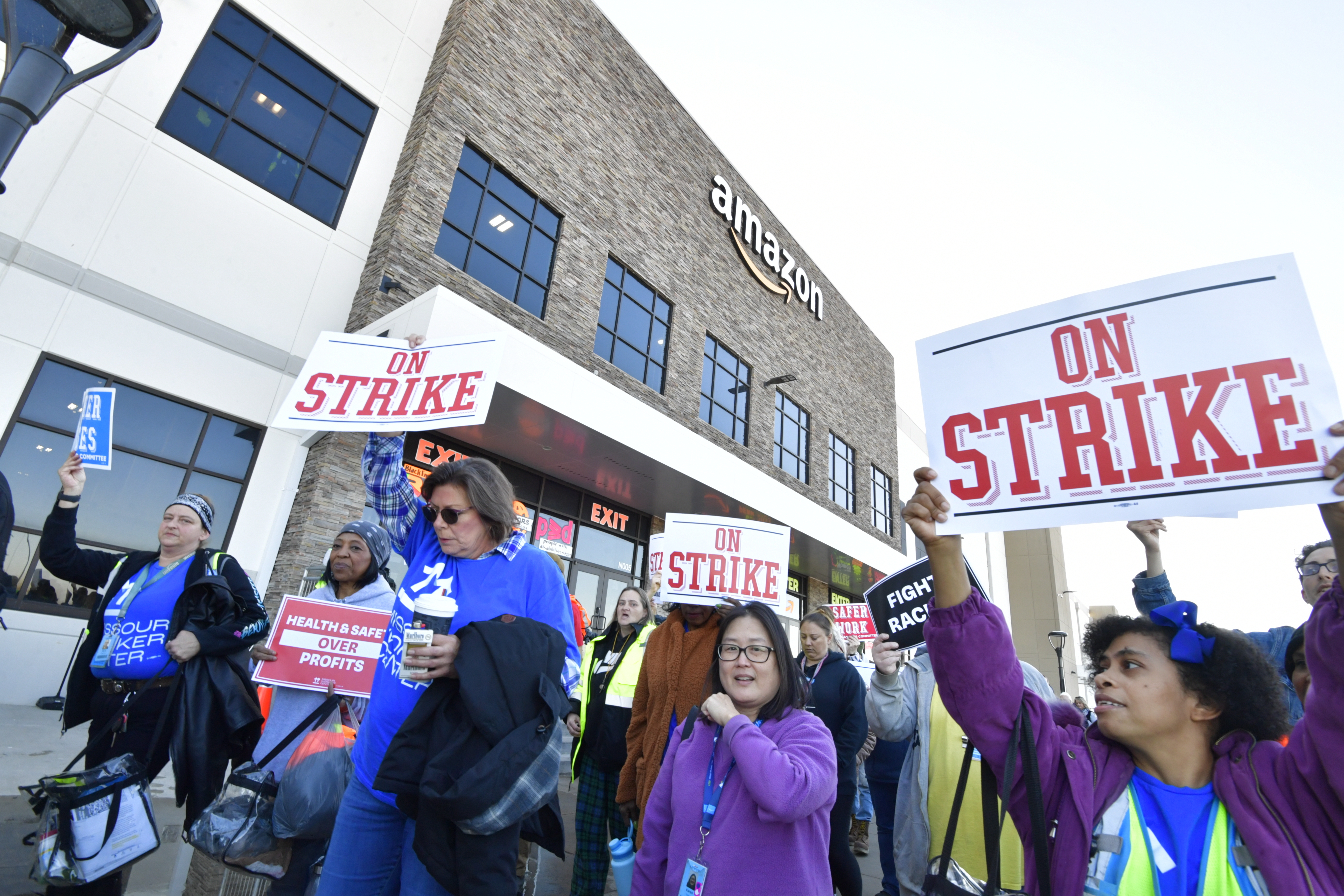 Workers outside Amazon offices hold signs saying 'ON STRIKE' and 'Health and Safety over Profits'