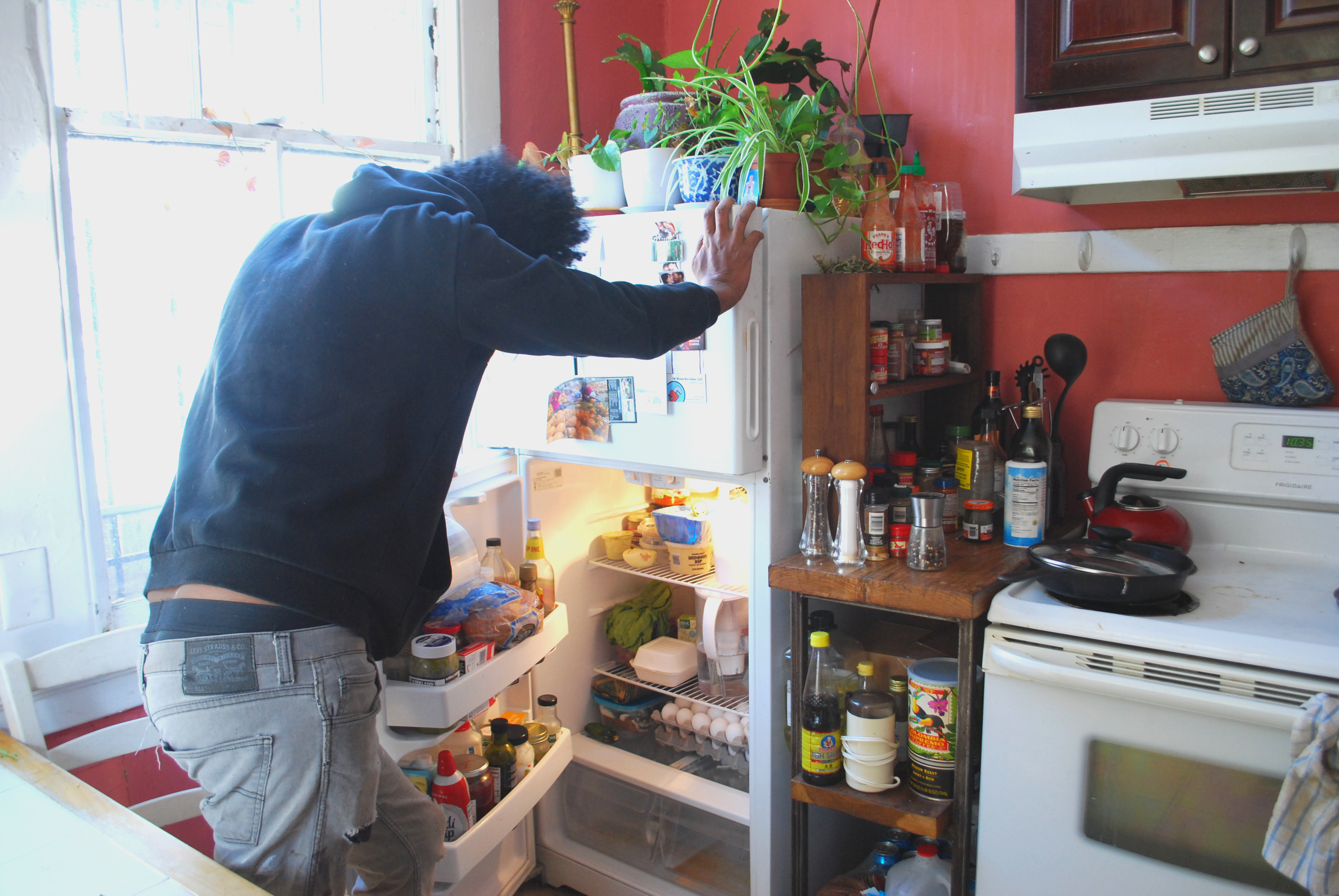 A photo of Aman looking through a refrigerator.