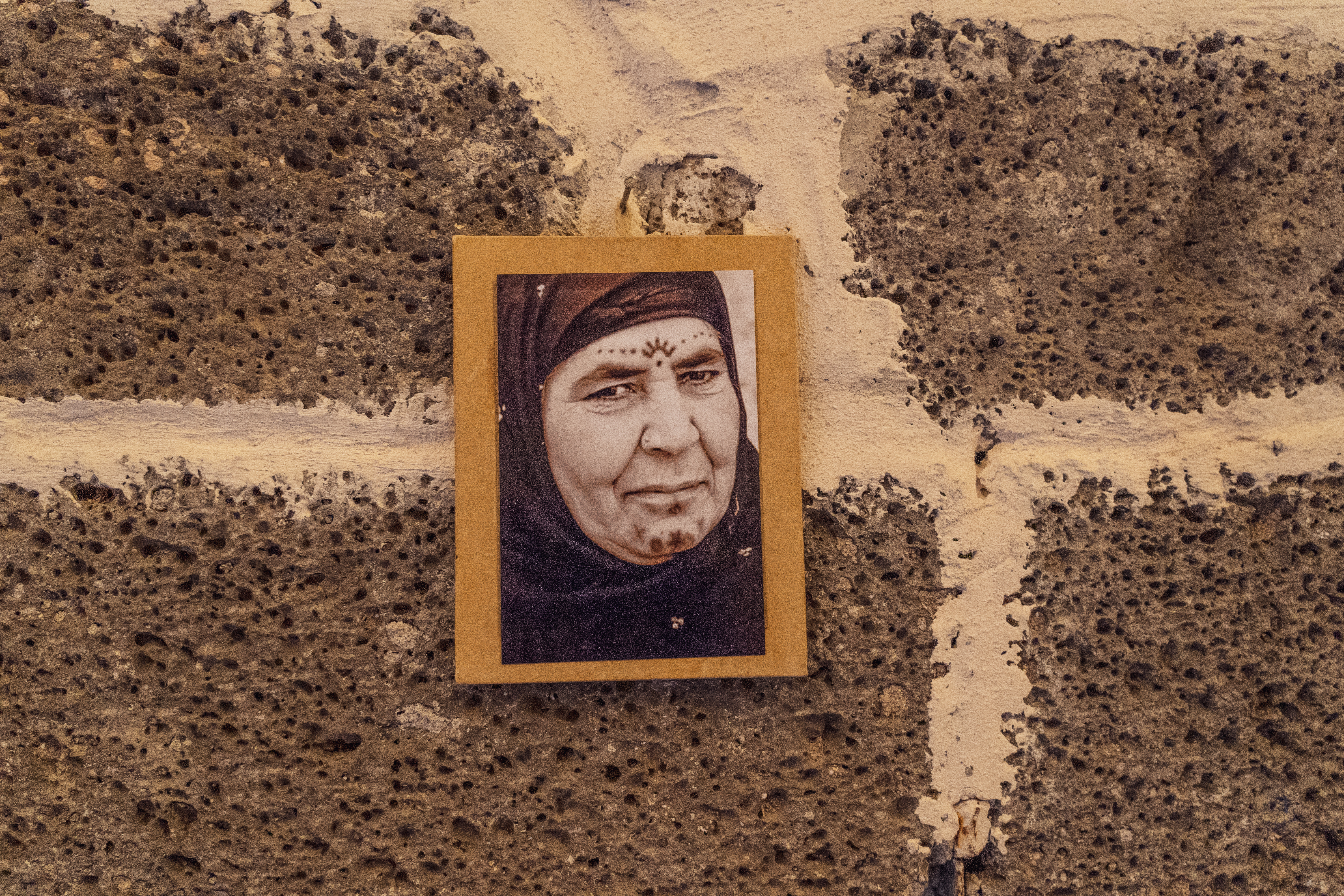 A photo of a photo hanging in Temel’s studio, showing an elderly woman adorning a symbolic sun motif on her forehead.