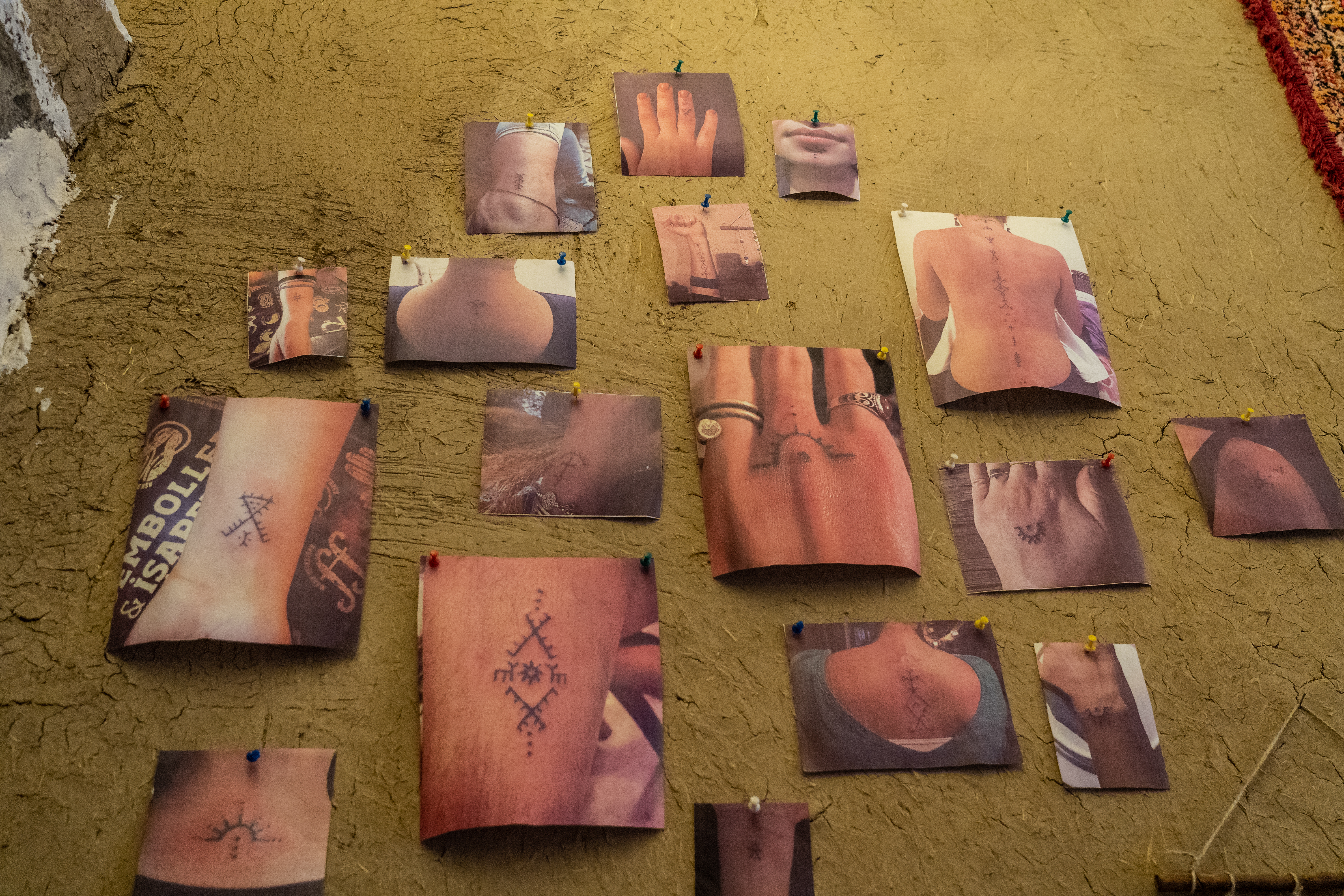 A photo of photos on the walls of a studio, showing traditional deq symbols and motifs