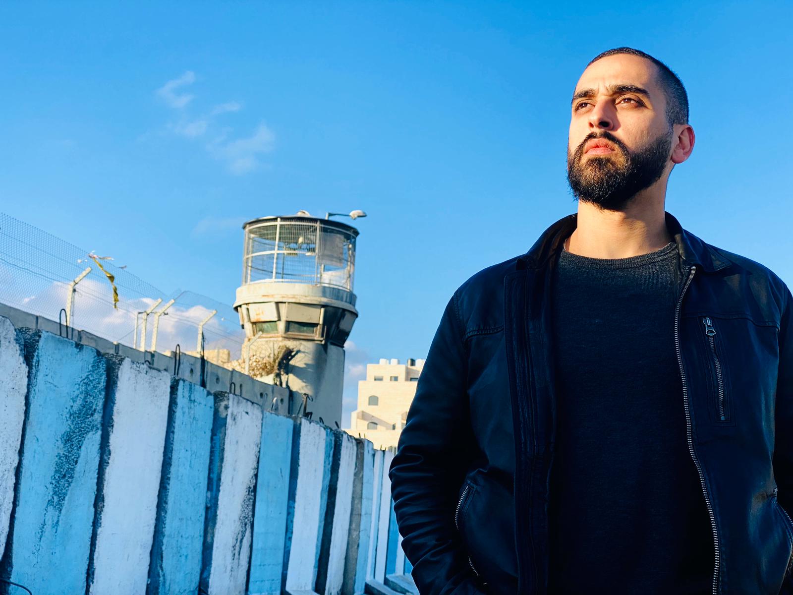 Fayez Kawamleh standing next to the Israeli separation wall.