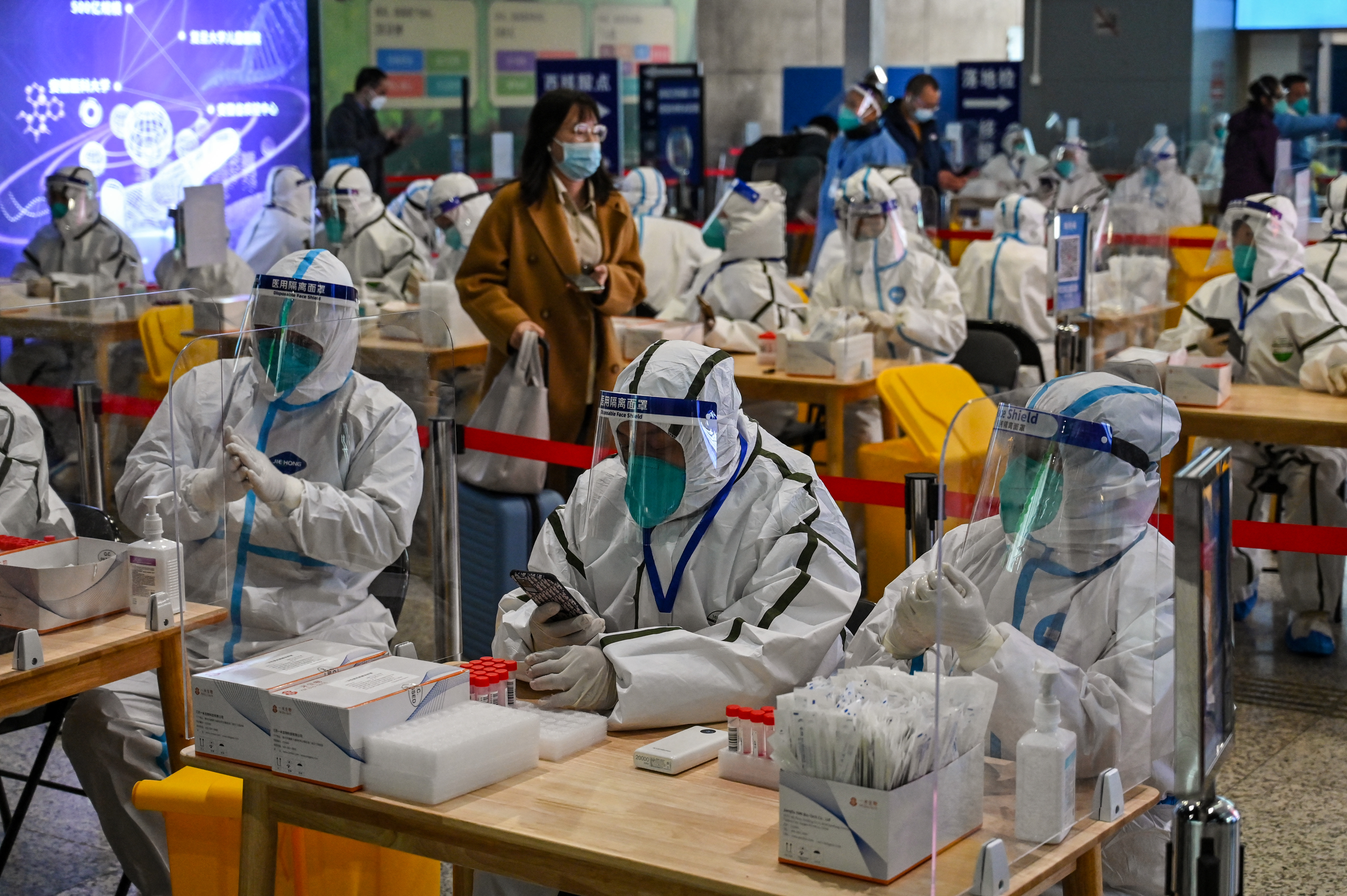 Health workers wait to test passengers for the Covid-19 coronavirus after their arrival at Hongqiao railway station in Shanghai, on December 6, 2022.