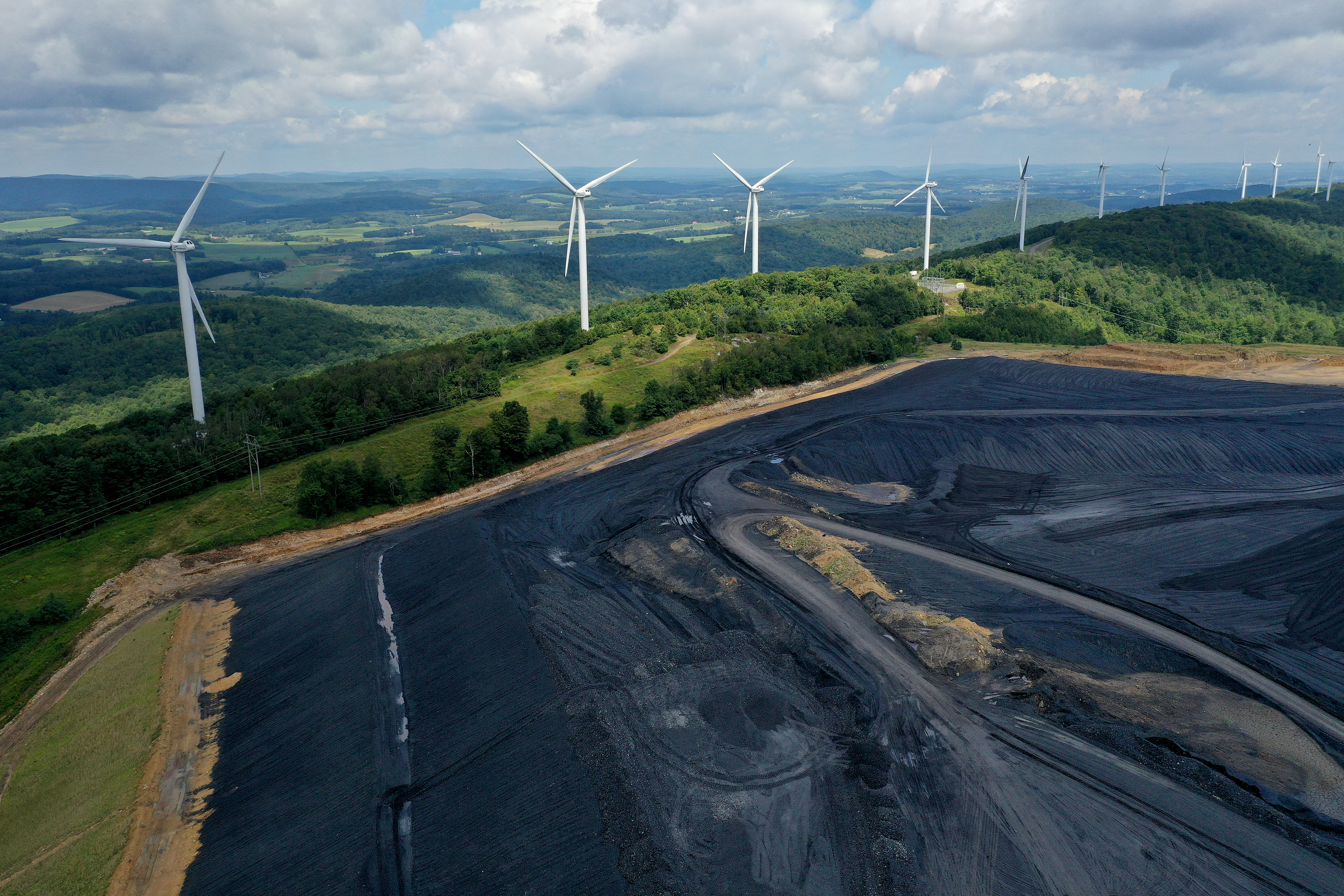 In an aerial view, turbines from the Roth Rock wind farm spin on the spine of Backbone Mountain