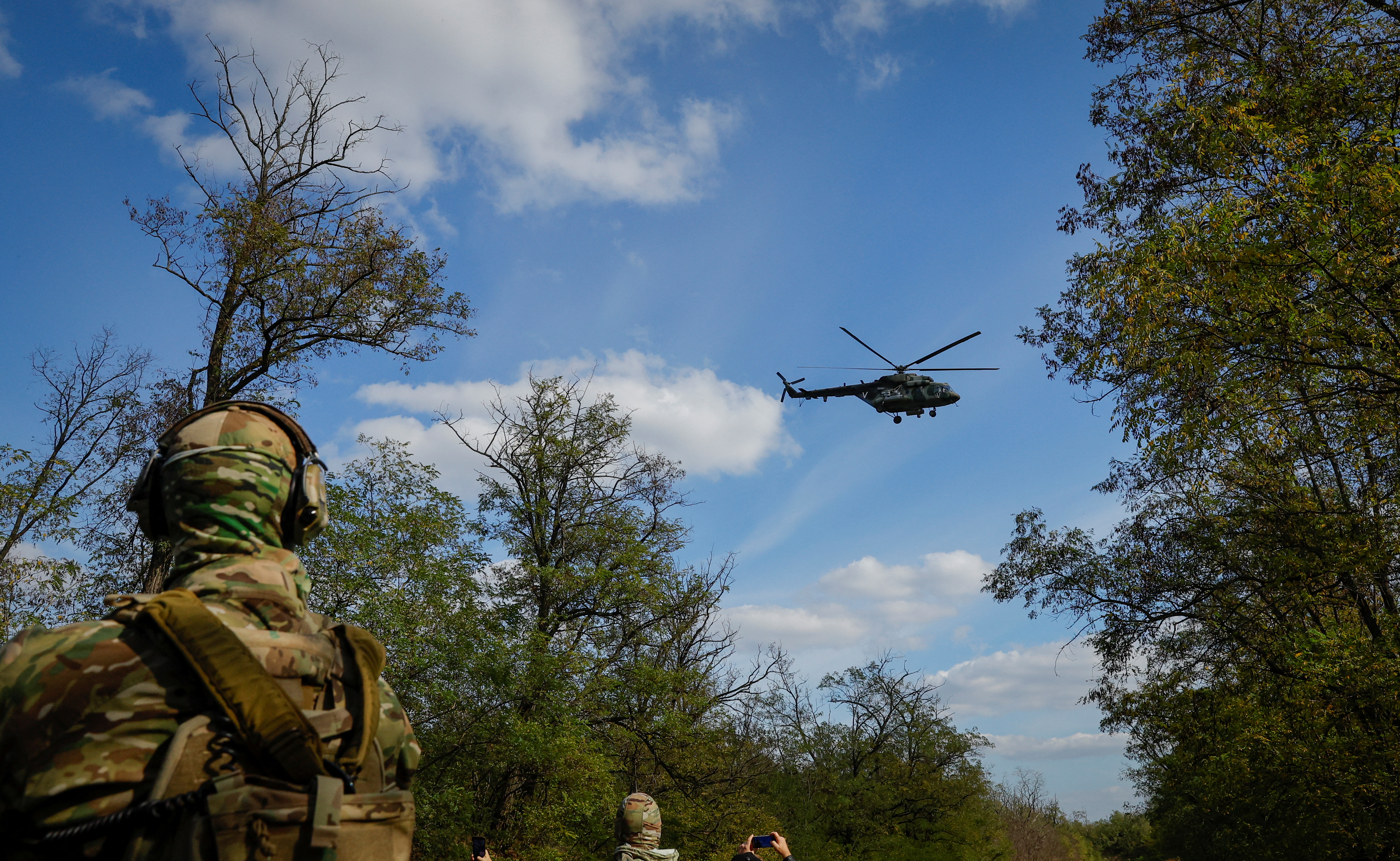 A Russian army helicopter flies above, as volunteers of a newly formed battalion take part in a training at a range outside the city of Melitopol, Russian-controlled Ukraine October 13, 2022. REUTERS/Alexander Ermochenko